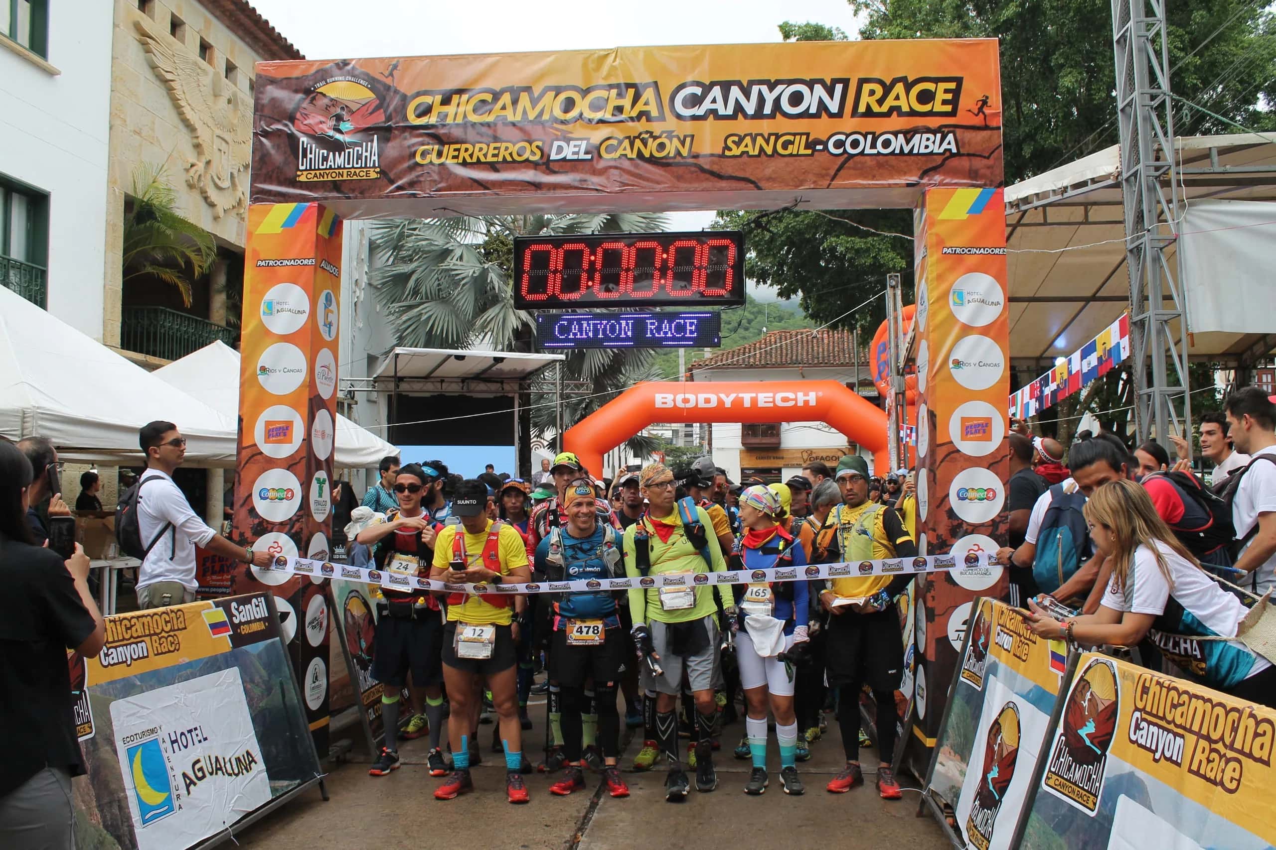 Runners ready on the start line under the race arch, with the official clock at zero