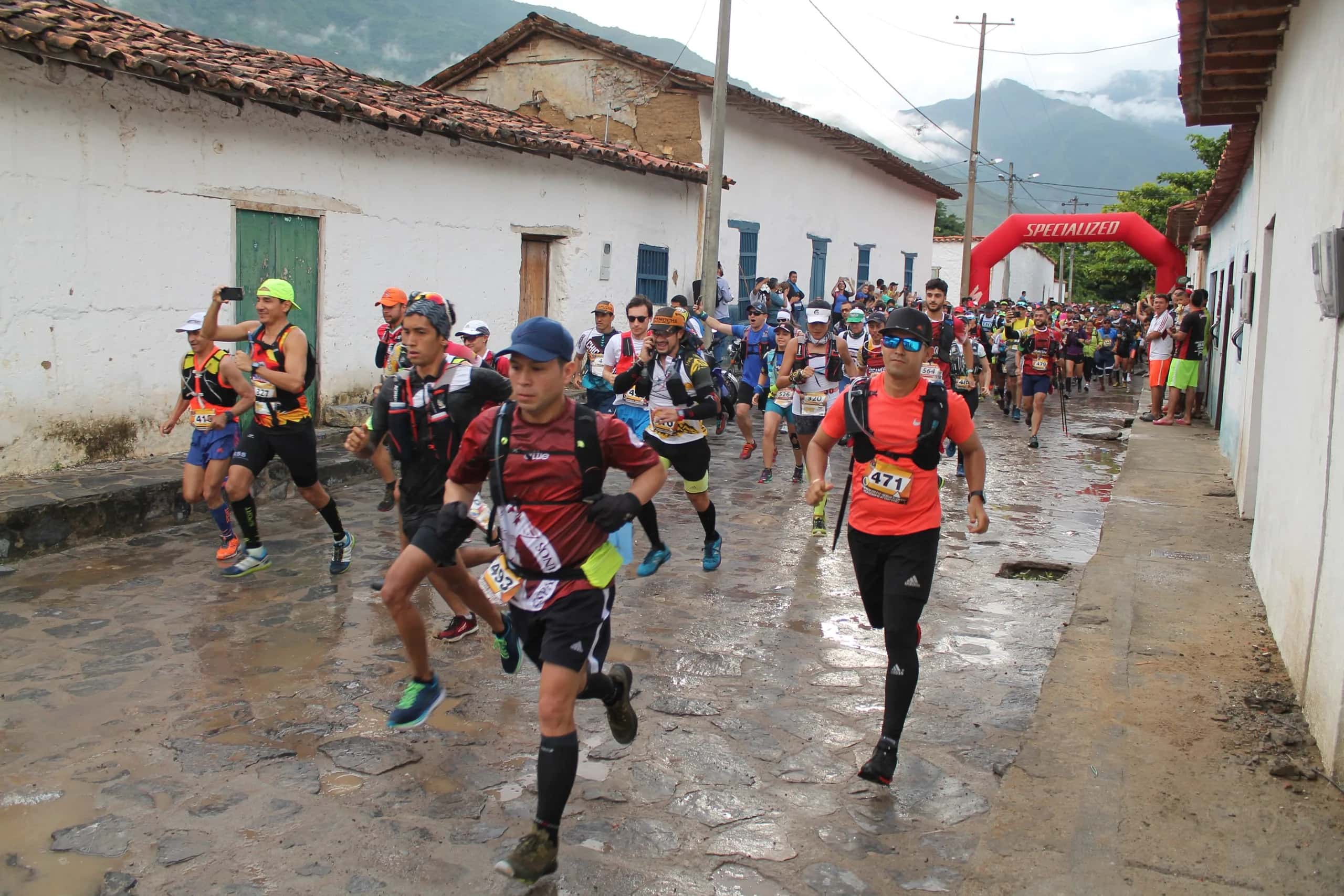 Runners set off along a wet village street lined with white houses and tiled roofs