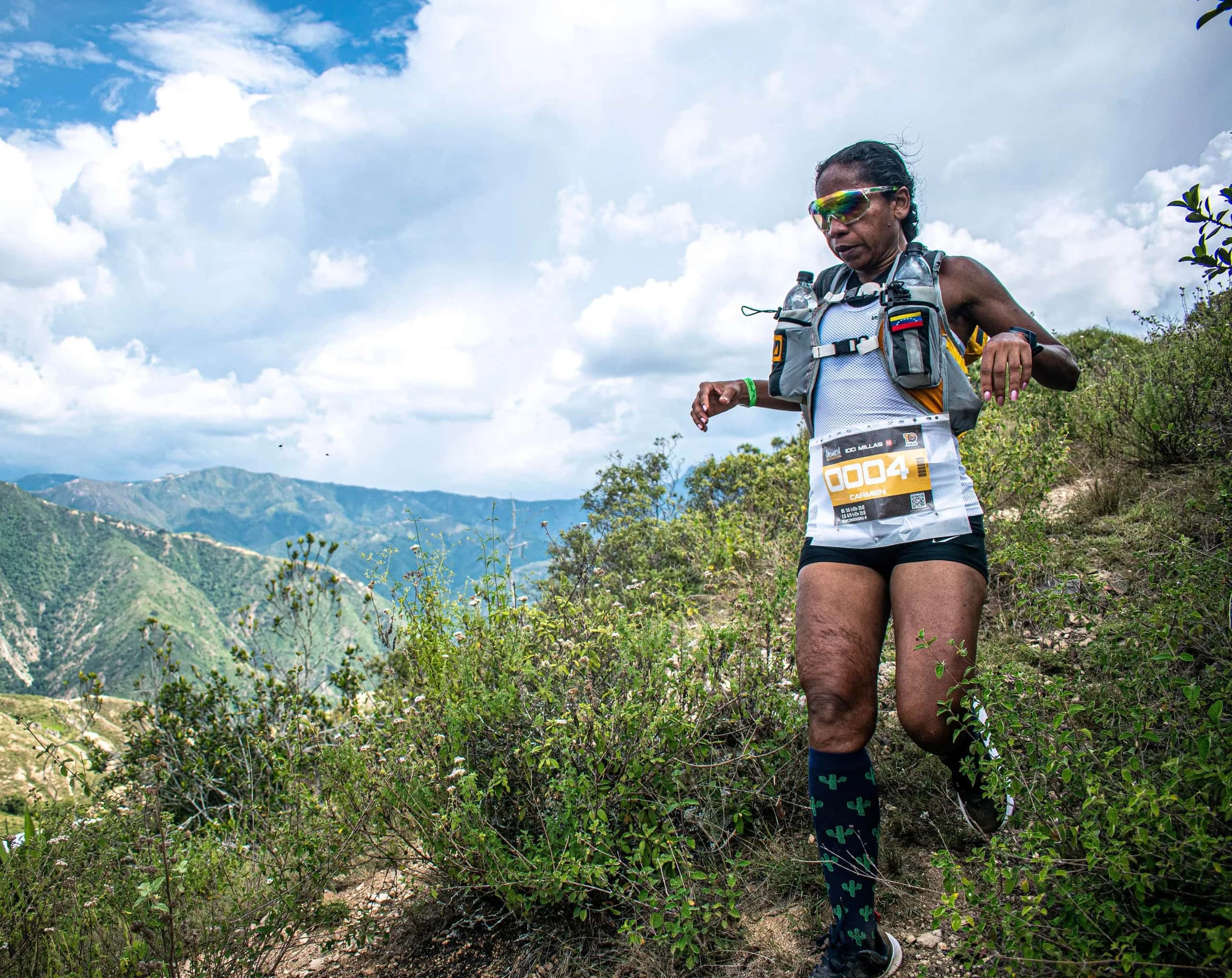 Runner descending a slope with the canyon mountains and a cloudy sky behind