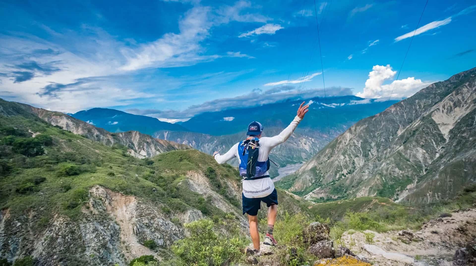 Runner with arms outstretched on a trail above the Chicamocha Canyon