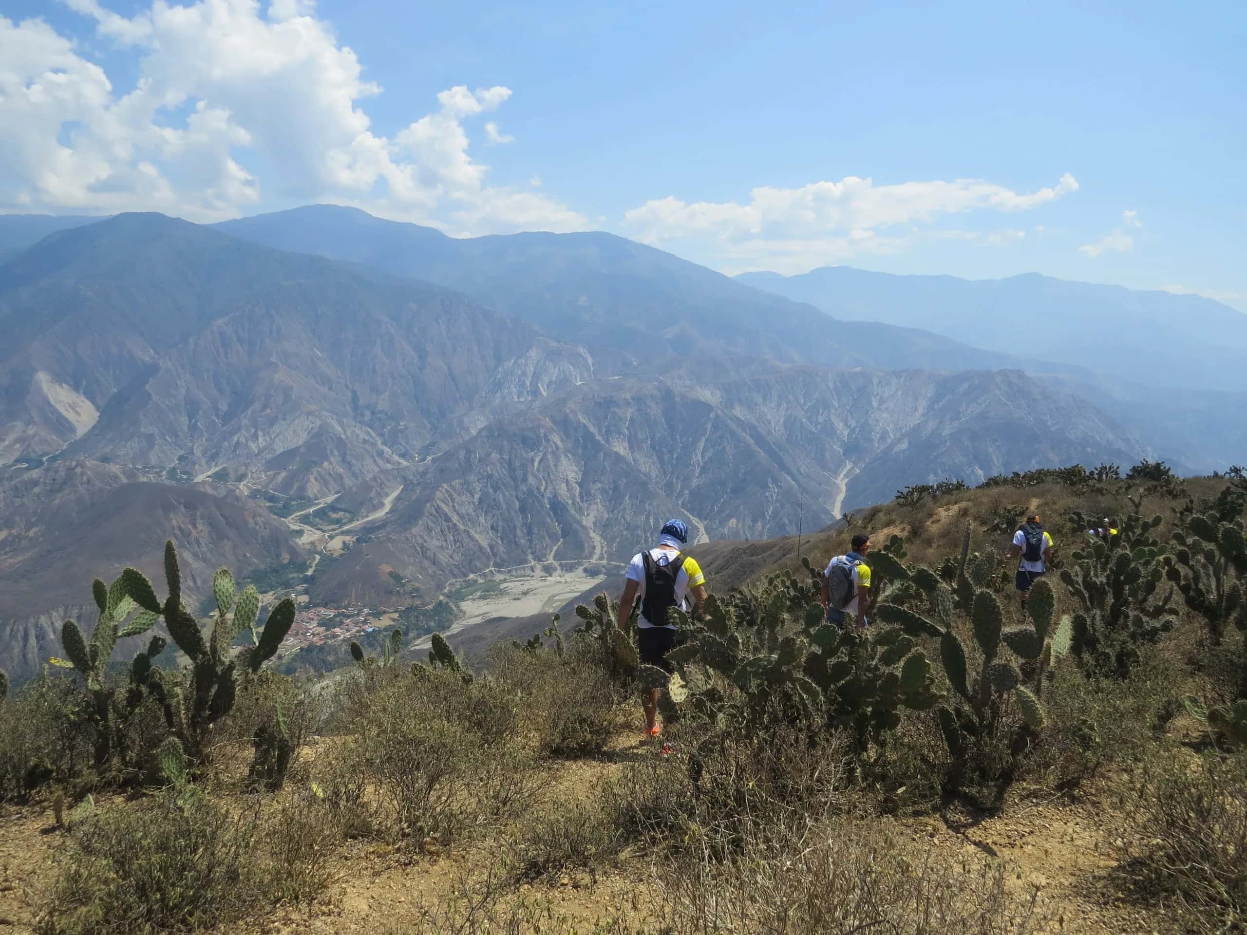 Runners among cacti on the rim of the Chicamocha Canyon, with blue mountains behind