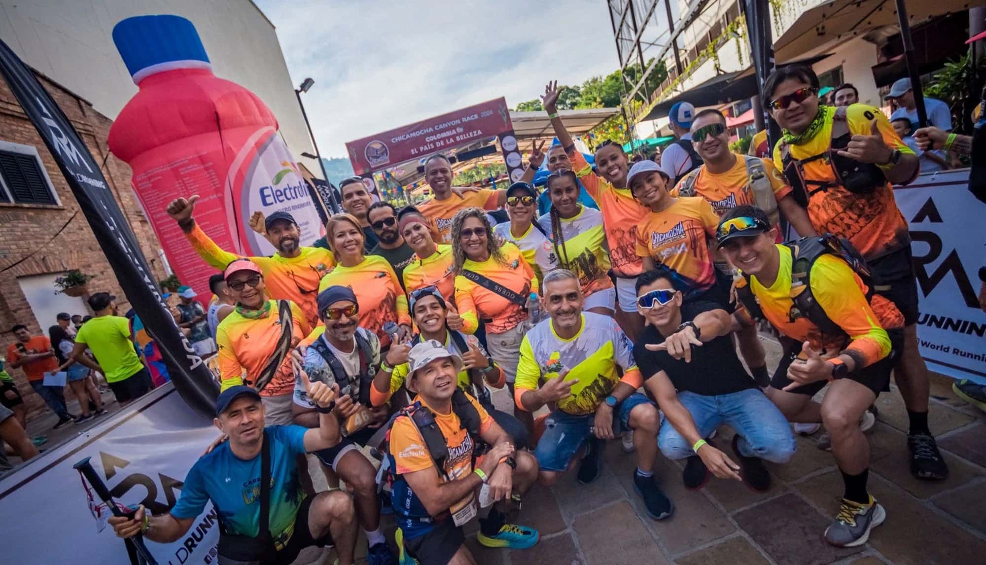 Group of runners in orange shirts celebrating next to the race arch