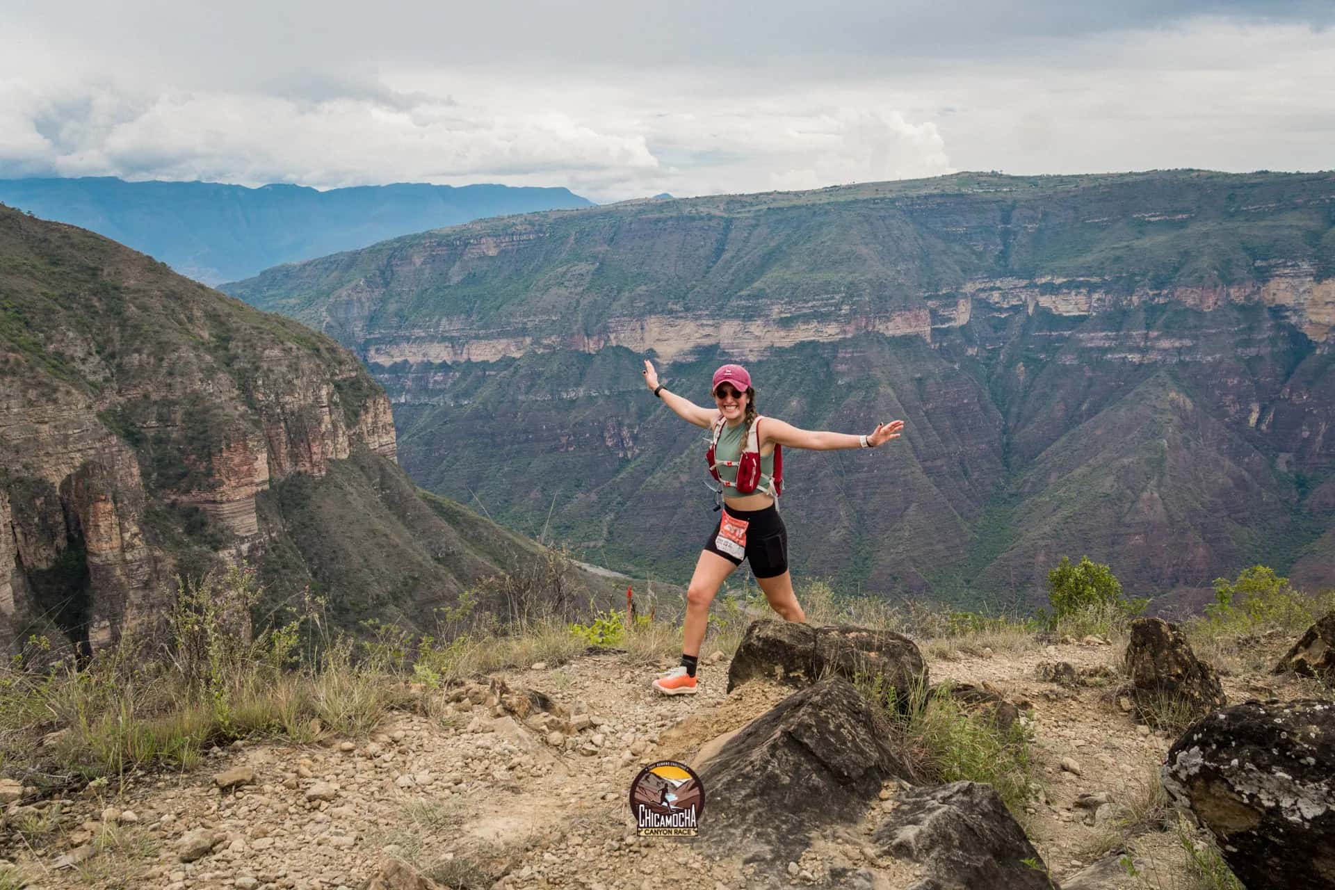 Corredora abre los brazos de alegría sobre una roca frente al cañón