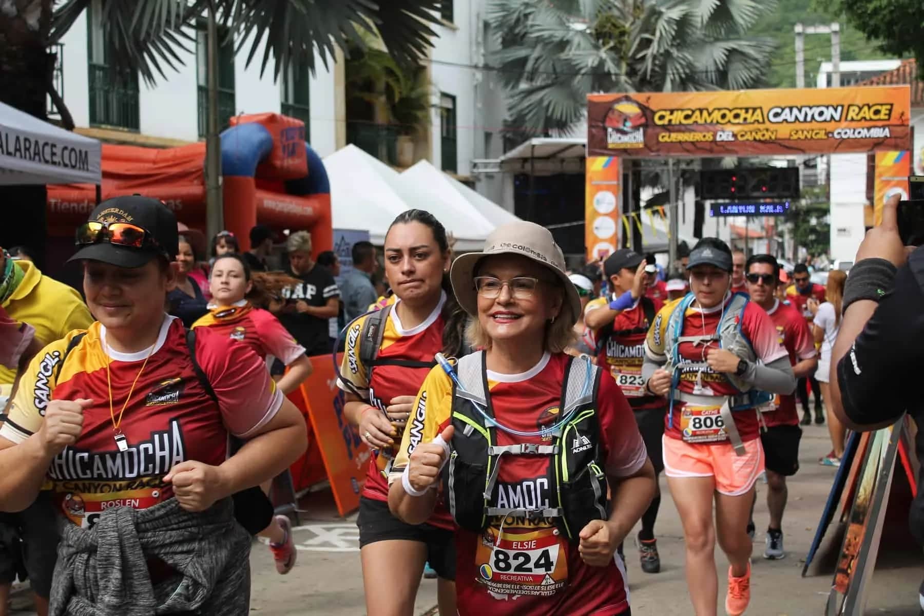 Smiling runners at the start, surrounded by spectators and tents