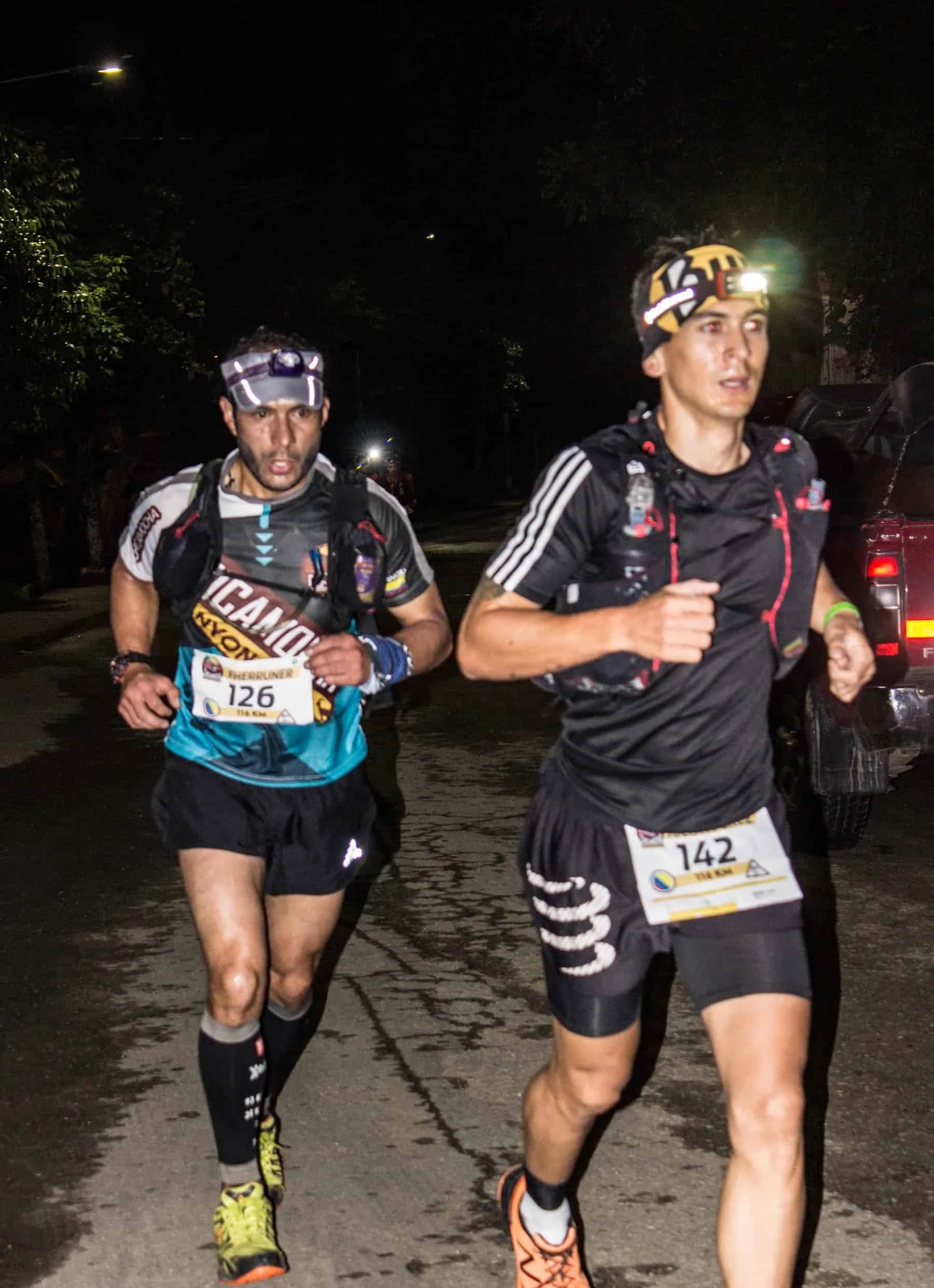 Two runners with headlamps pushing on through the night