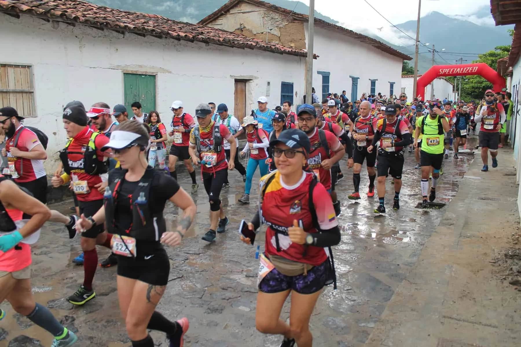 A pack of runners sets off along a wet village street lined with white houses