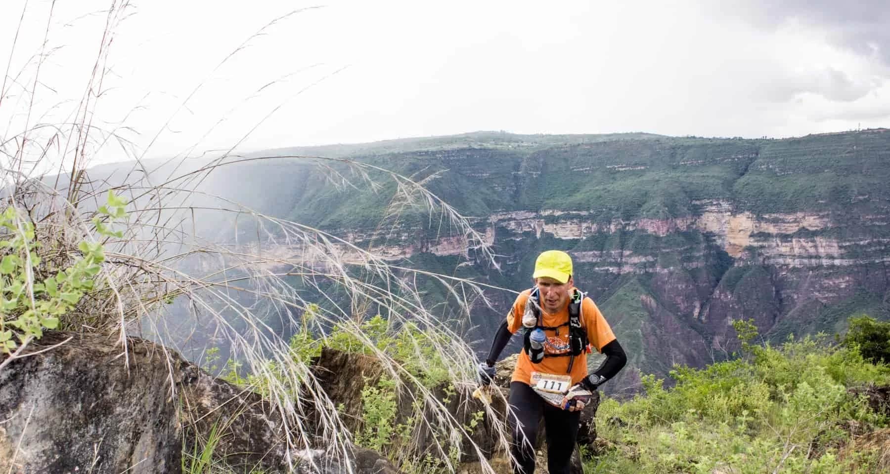 Runner emerging from the vegetation with mist over the canyon walls