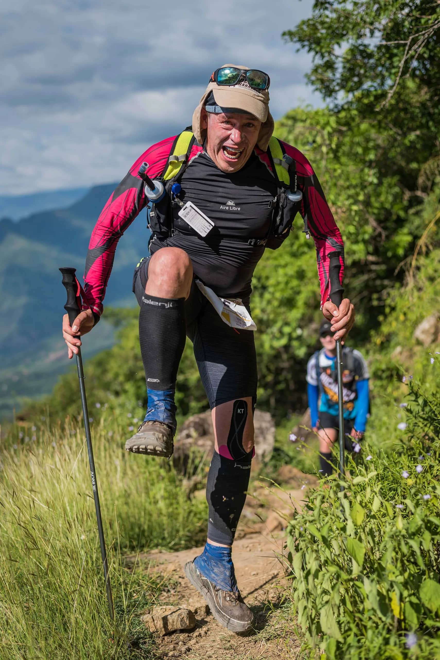 Runner with poles powering up a steep mountain trail