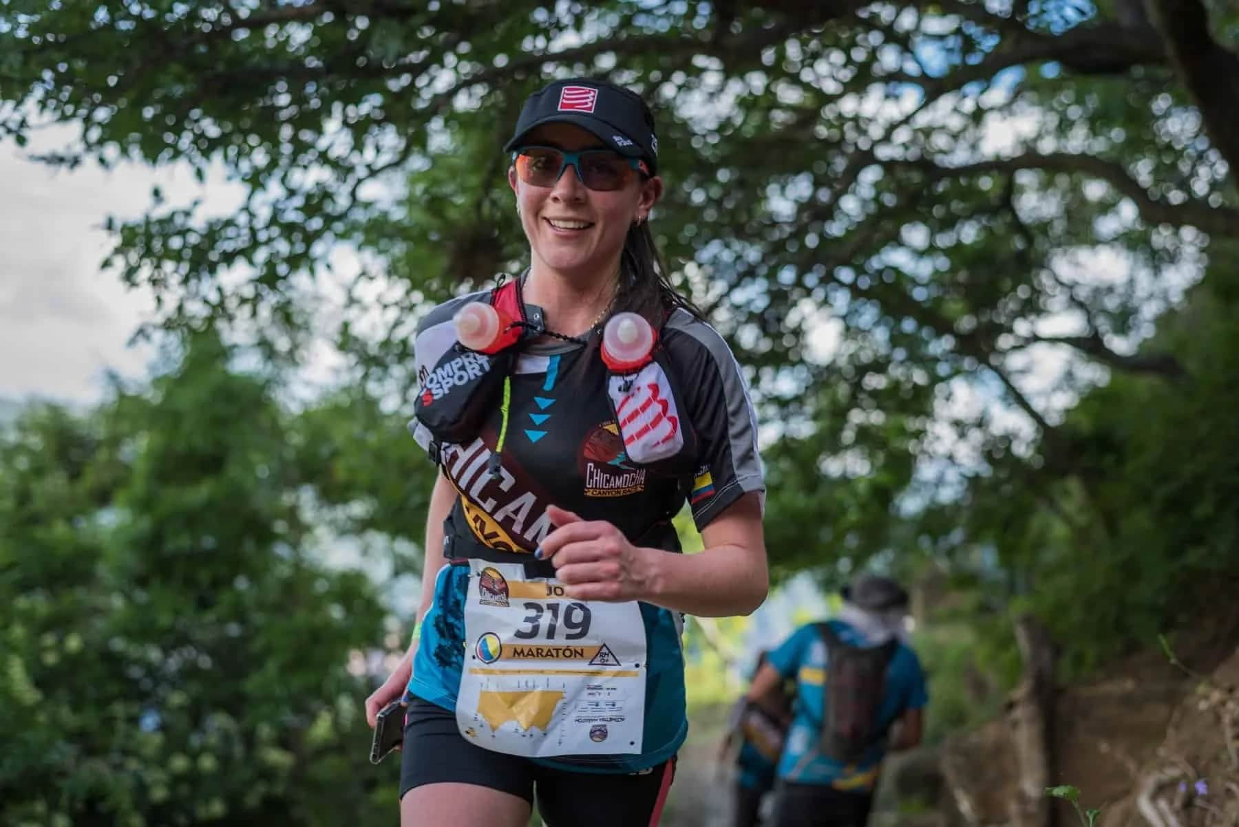 Smiling runner wearing marathon bib 319 on a tree-lined trail
