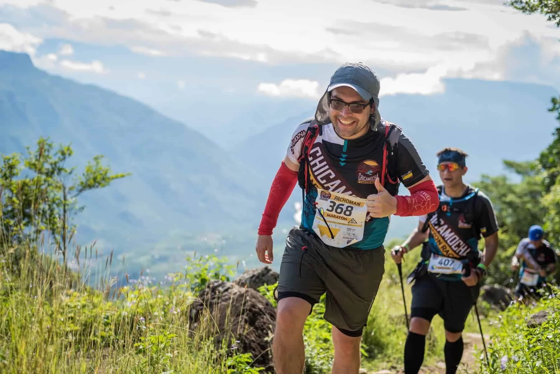 Runner smiling with a thumbs up on a mountain trail