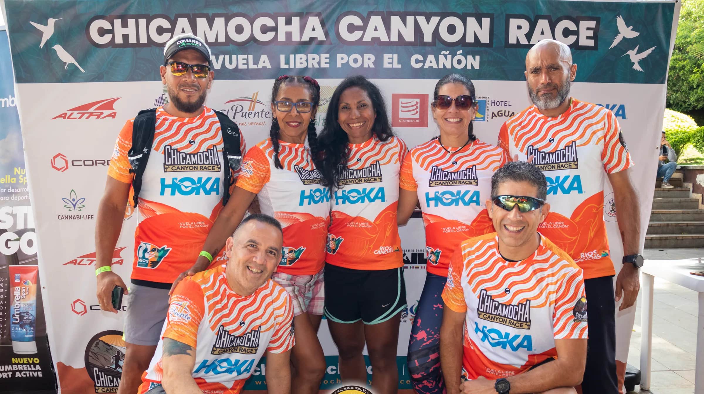 Group of runners in the official shirt posing in front of the race backdrop