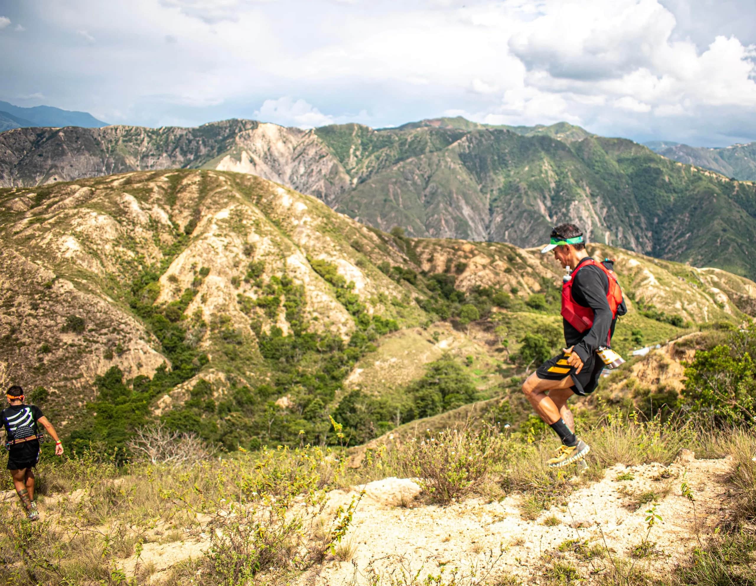 Runner crossing ochre, eroded slopes high above the canyon
