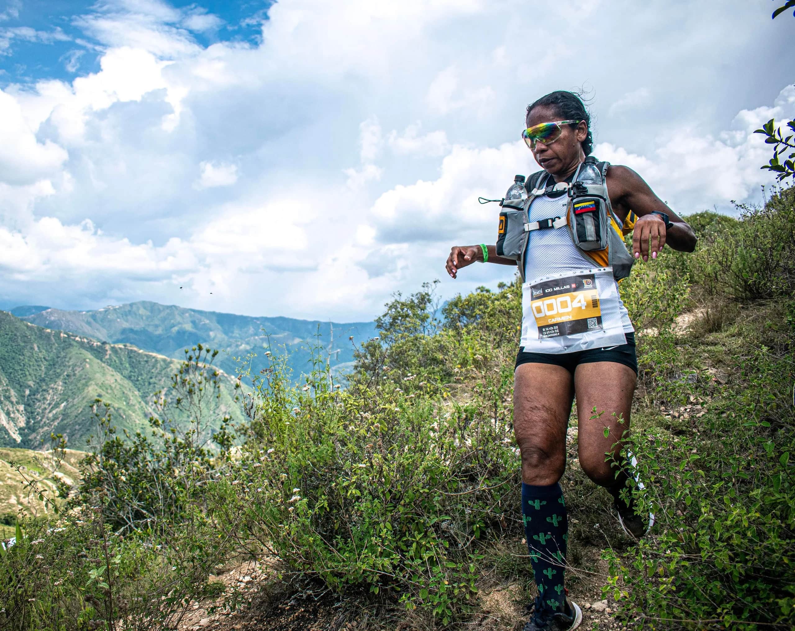 Runner descending a slope with the canyon mountains and a cloudy sky behind