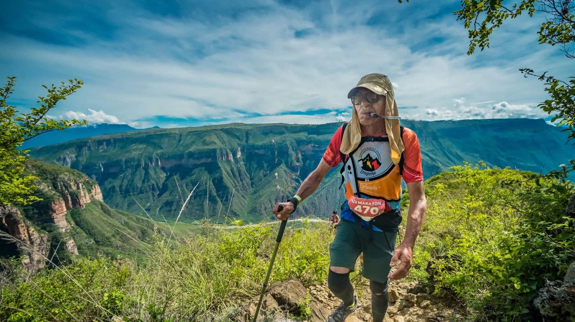 Runner with a hat and pole on the canyon rim