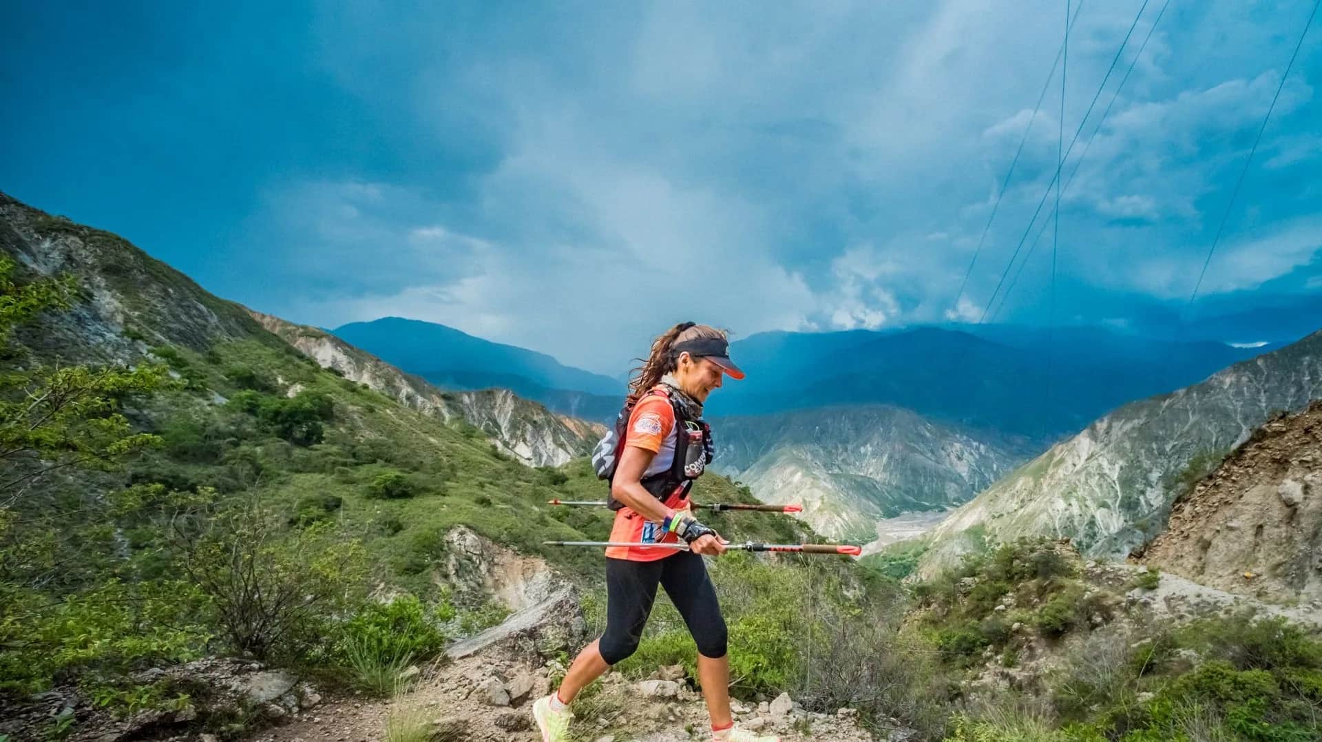 Runner with poles crossing a slope in front of the canyon mountains