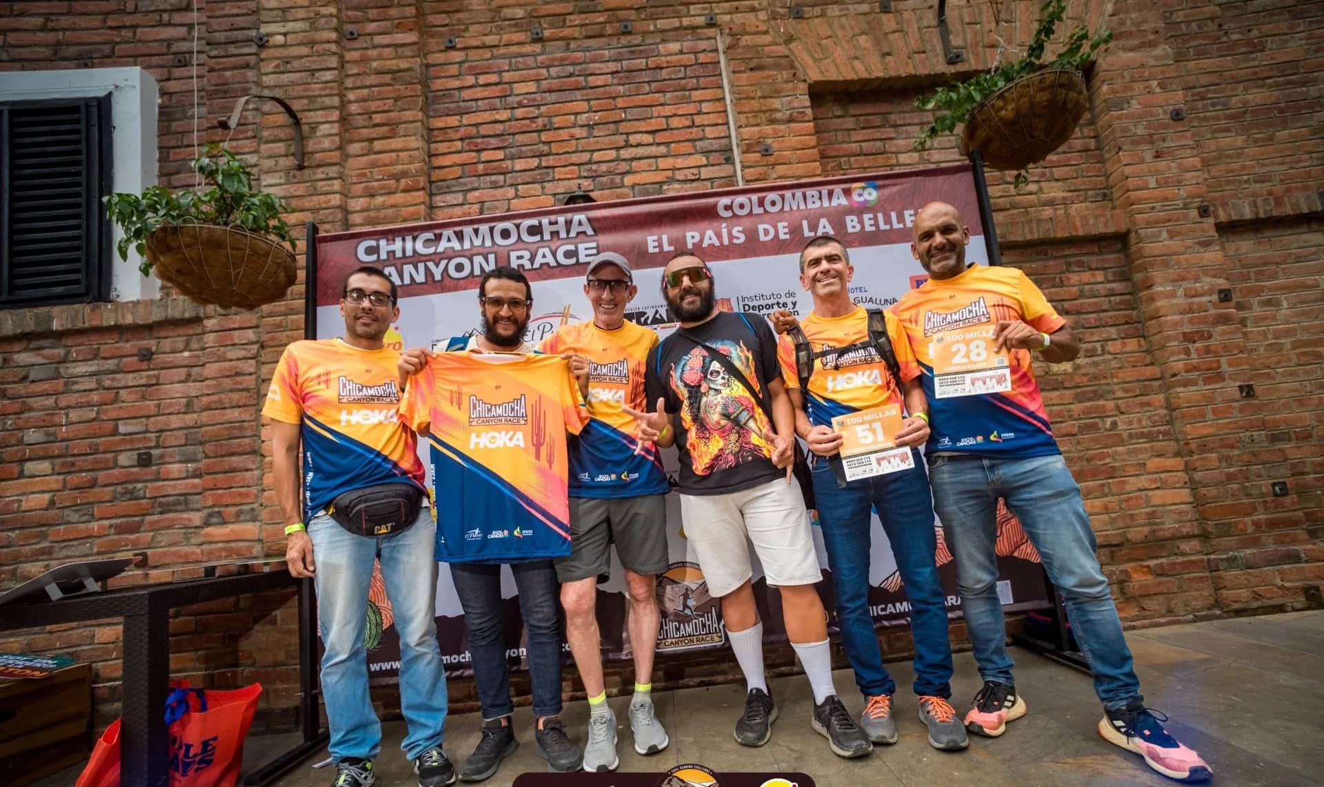 Group of runners in the 2024 shirt posing in front of the Colombia, the country of beauty backdrop