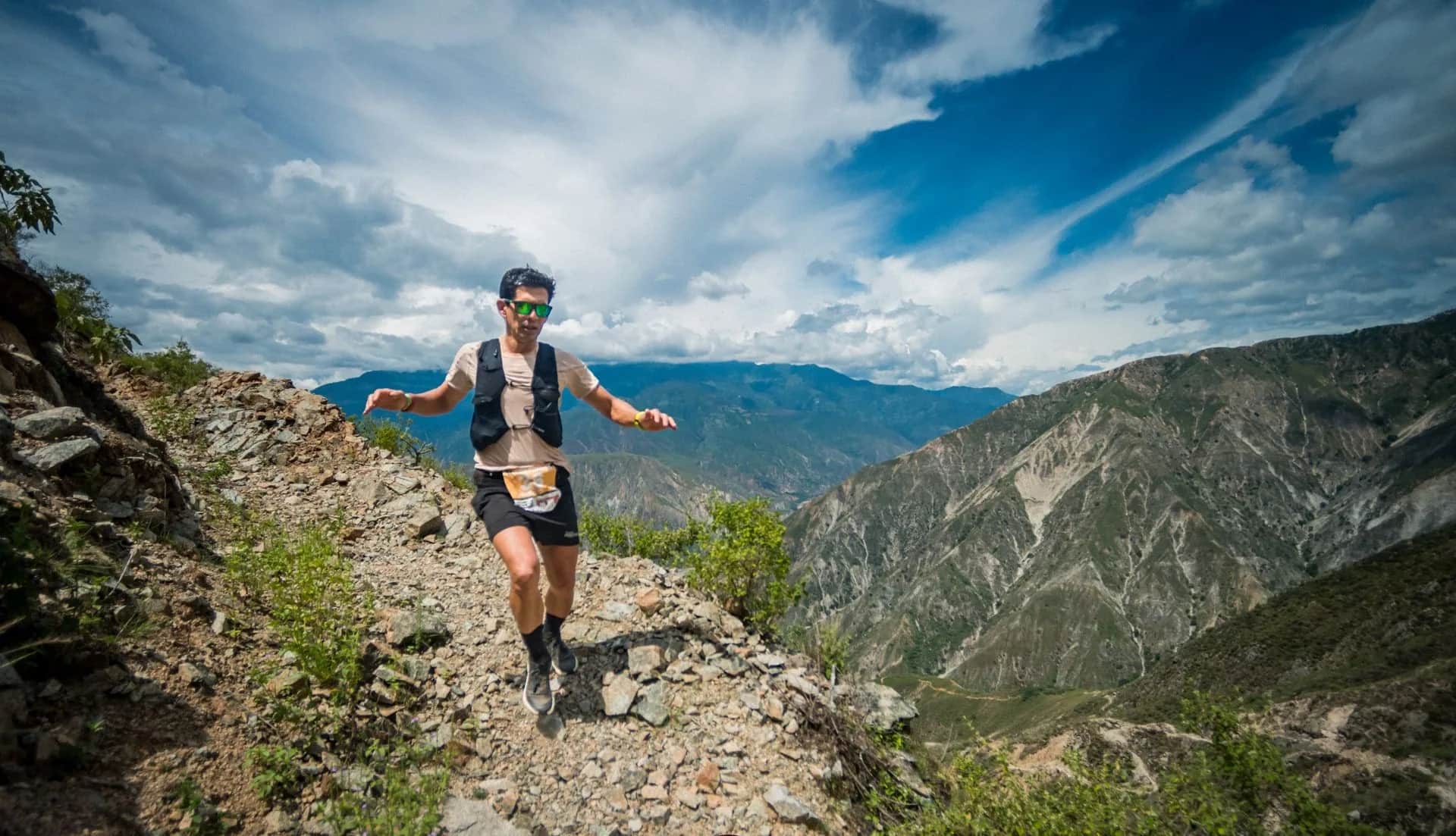 Runner descending a rocky ridge with canyon mountains on both sides