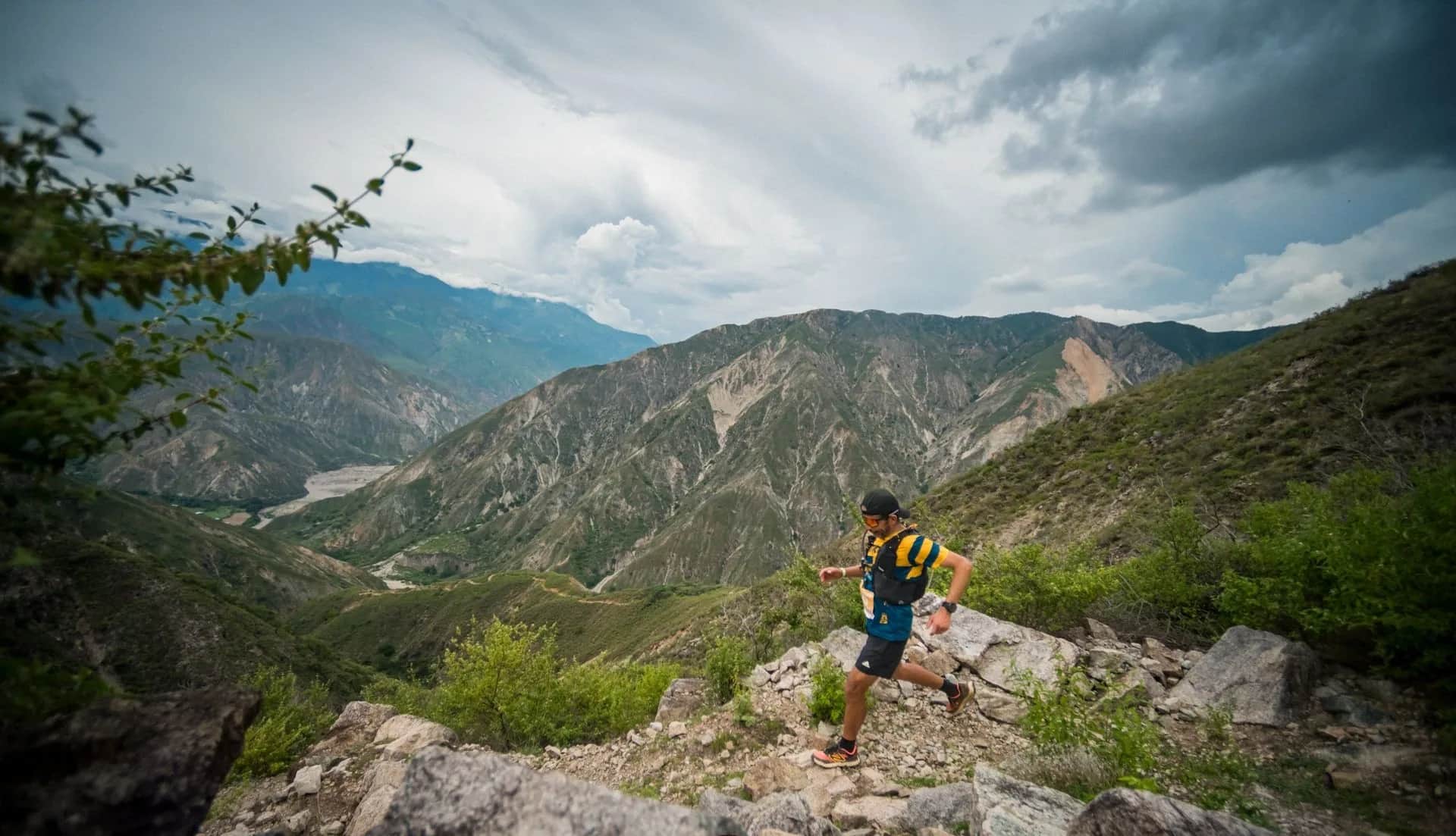 Runner moving between rocks on a hillside trail with the canyon beyond