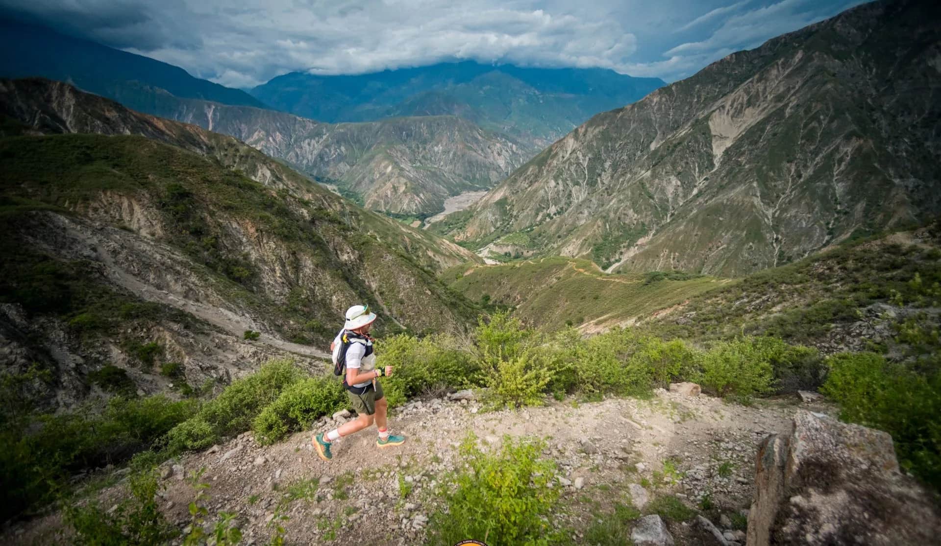 Runner on a rocky trail dropping into a deep canyon valley