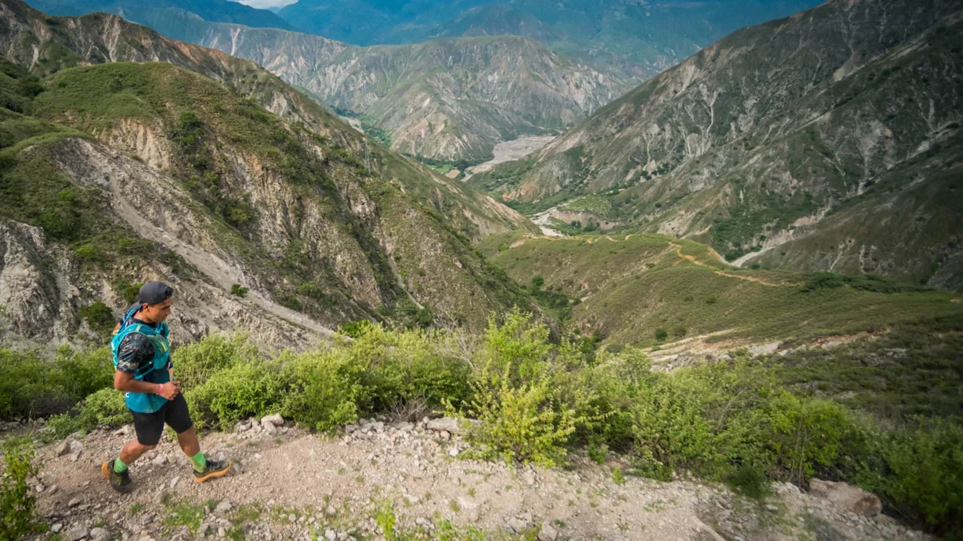 Runner on a hillside trail with the canyon valley opening below