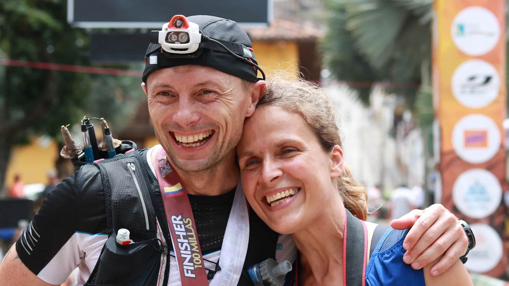 100-mile finisher, medal around his neck, hugs his supporter with a big smile