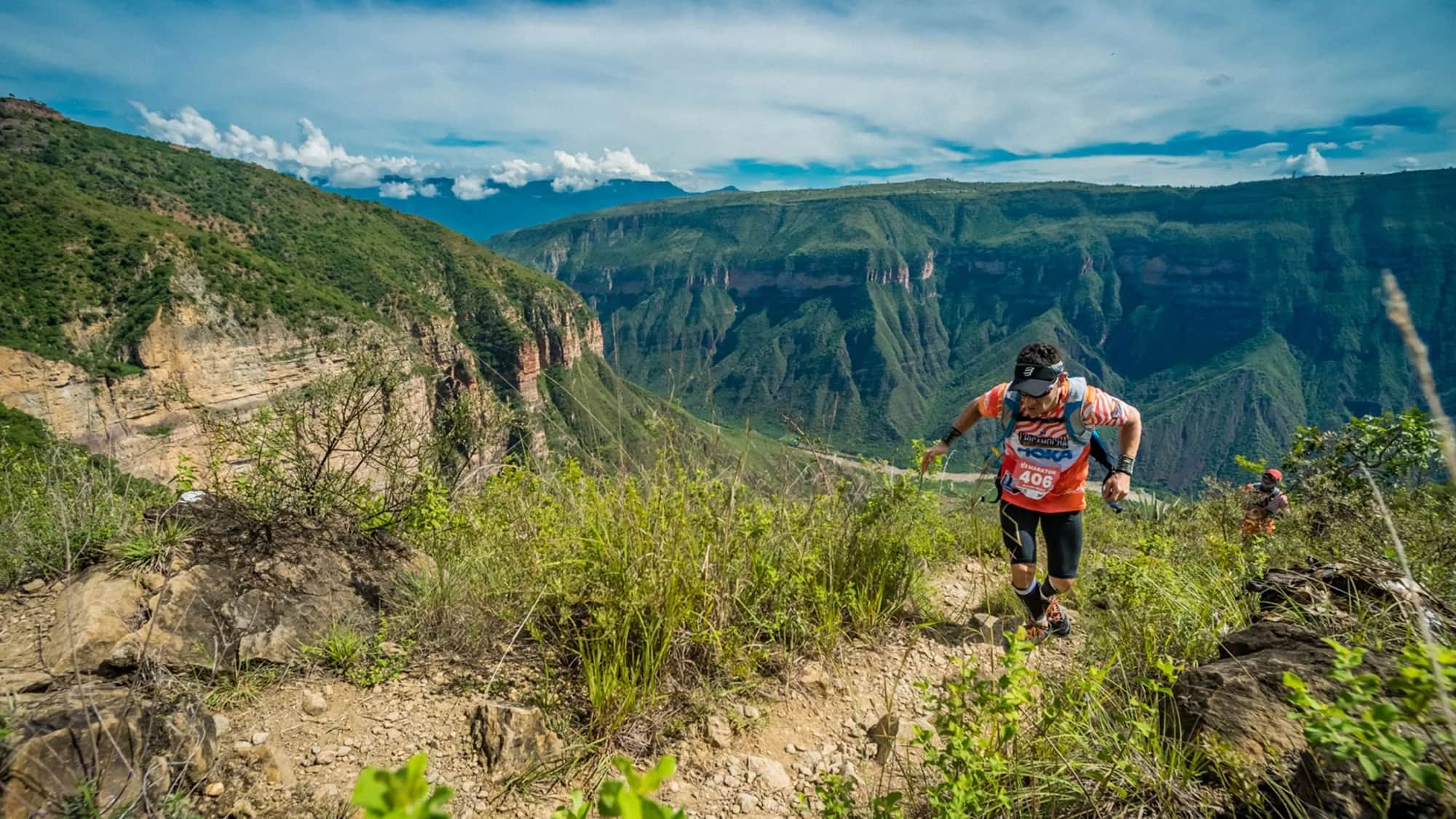 Runner climbing along the canyon edge, facing its vast green walls