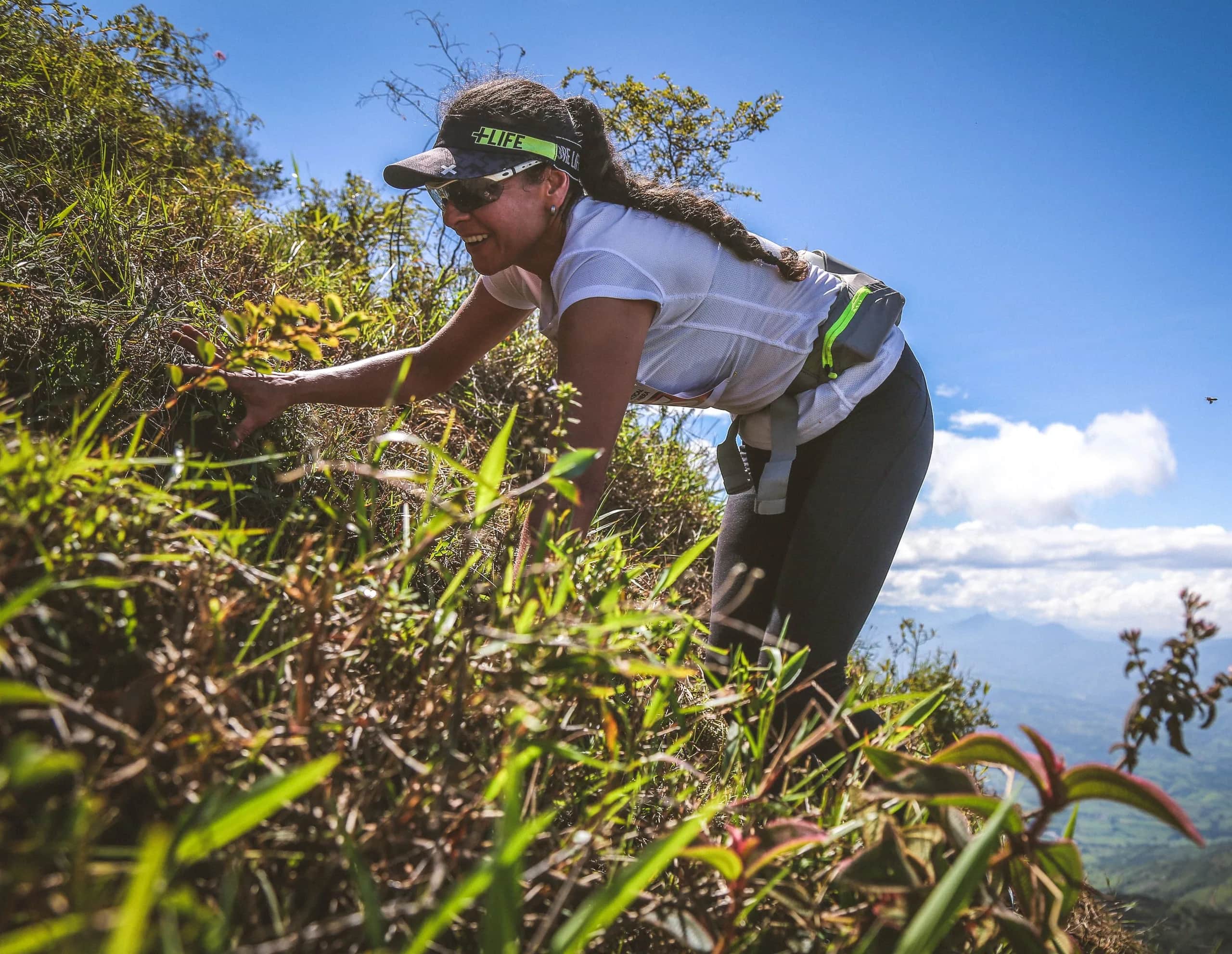 Runner grabbing the vegetation to climb a very steep section