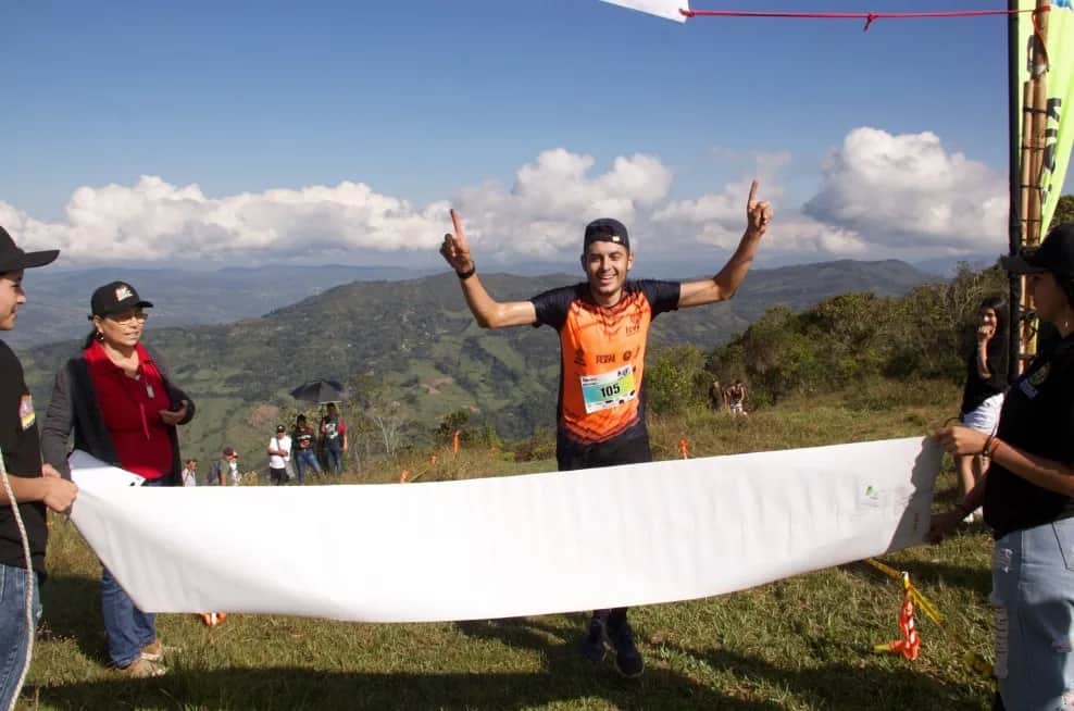Runner celebrating with arms raised as he crosses the finish line on the summit