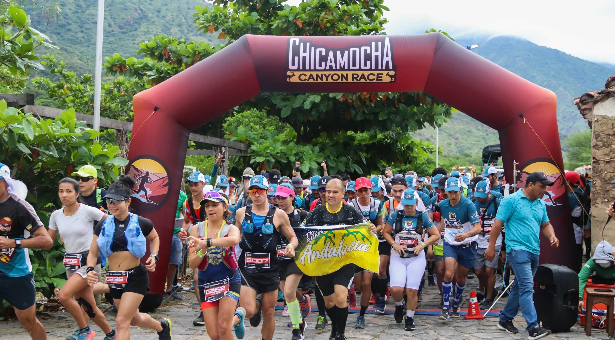 Runners starting under the Chicamocha Canyon Race arch on a cobbled street