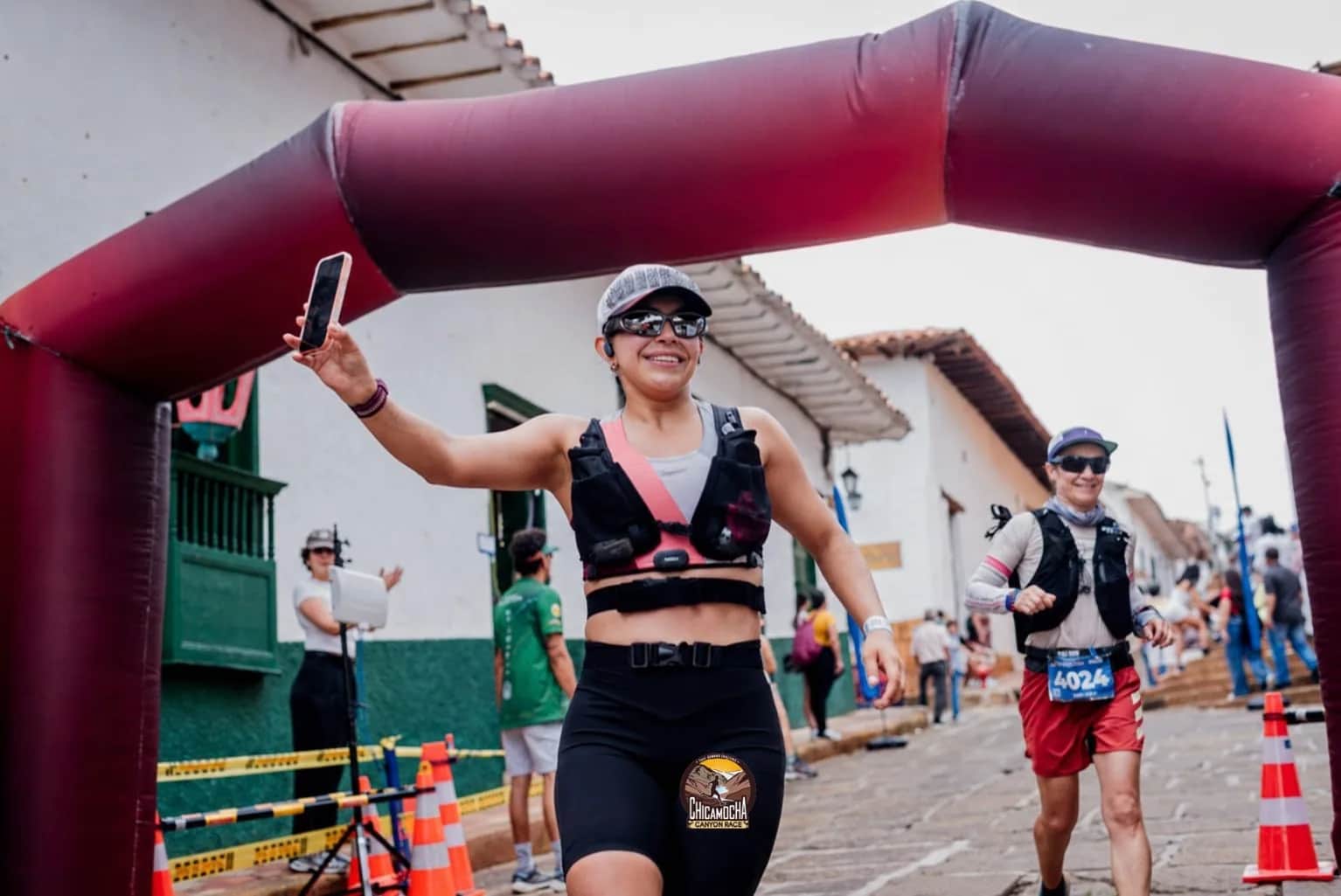 Runner celebrates as she arrives under the race arch on a colonial street in Barichara