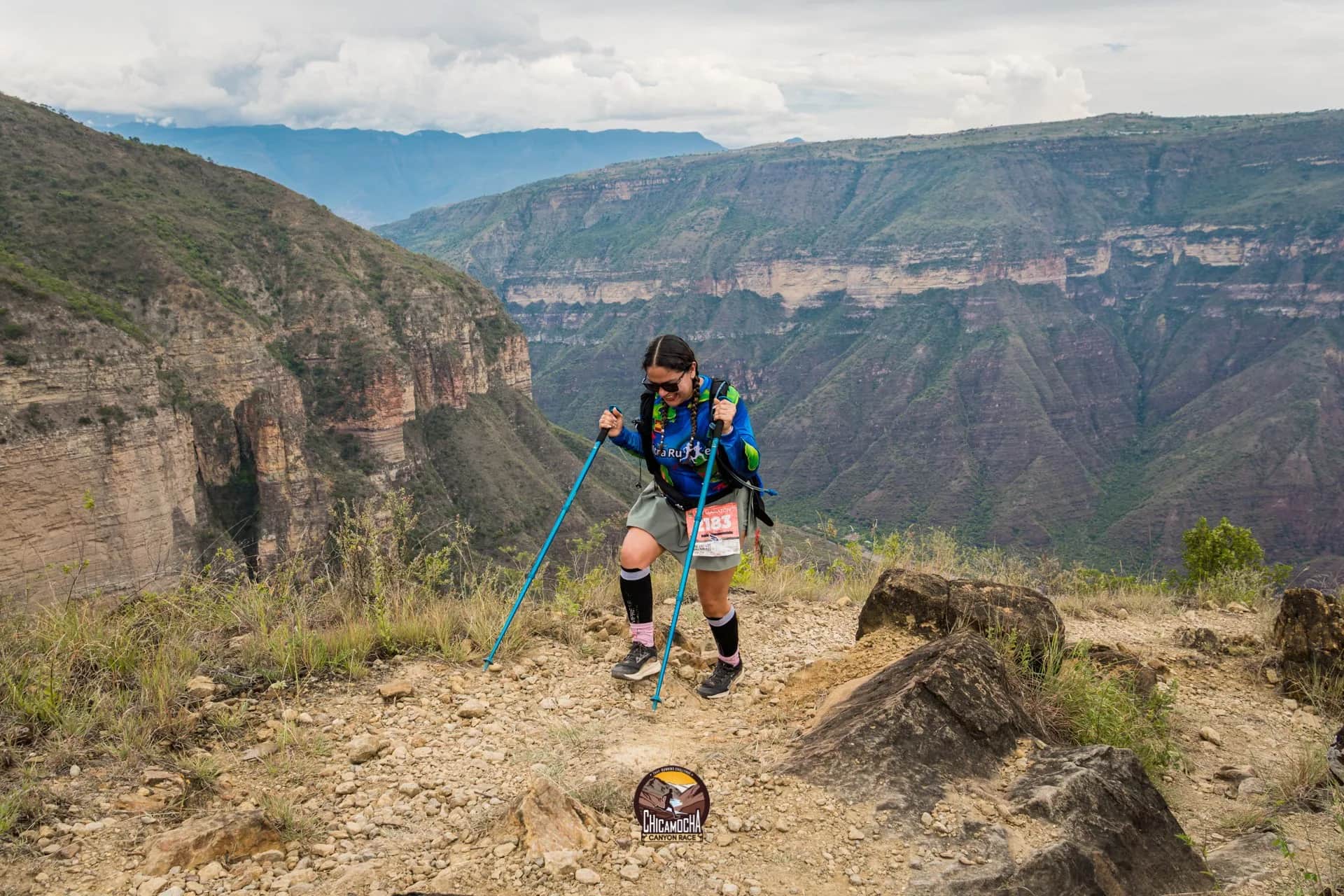 Corredora con bastones sube por el borde del Cañón del Chicamocha, con sus paredes al fondo