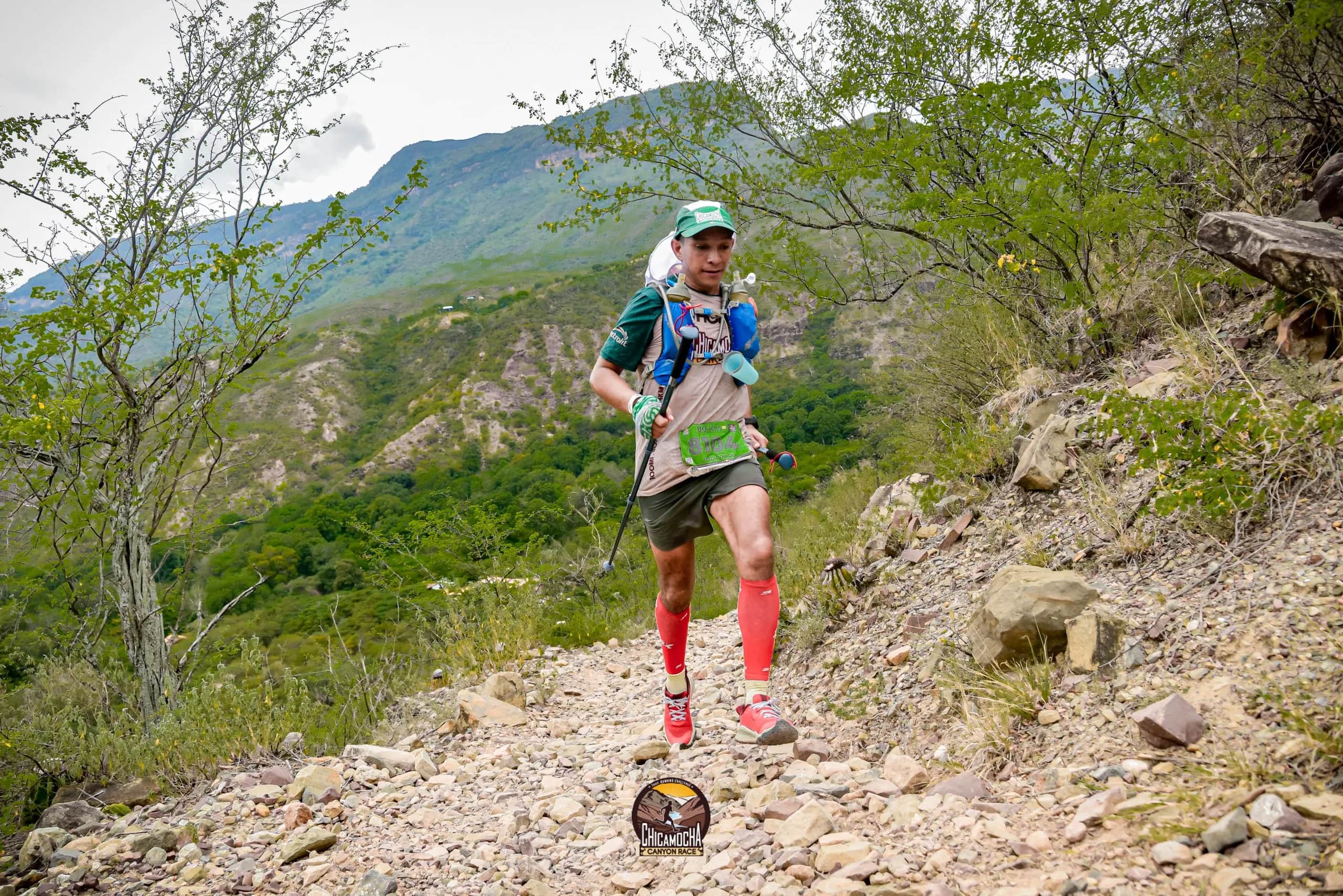 Runner in red socks descending a stony trail among trees