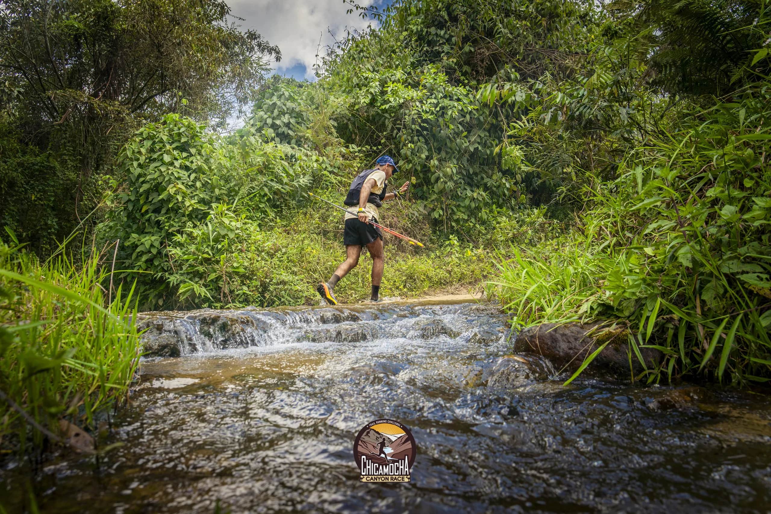 Runner crossing a small stream through the greenery