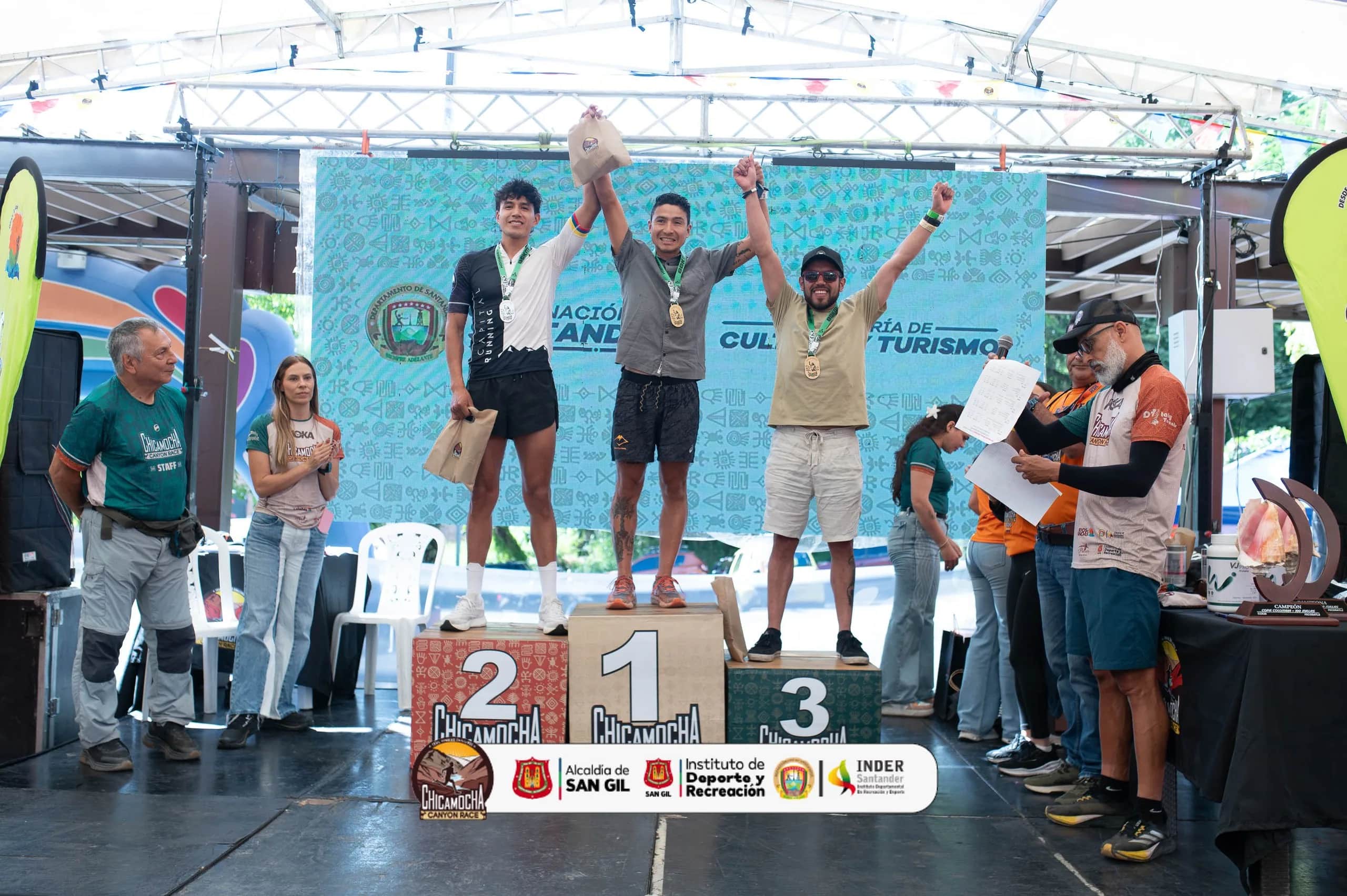 Men’s podium: three runners raise their arms with their medals