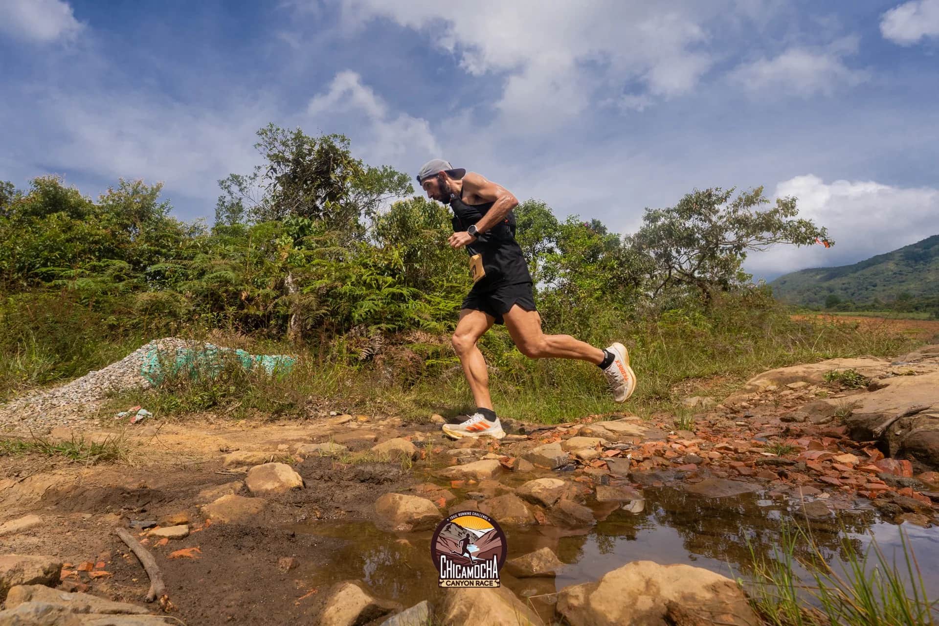 Corredor cruza un charco en un sendero entre arbustos