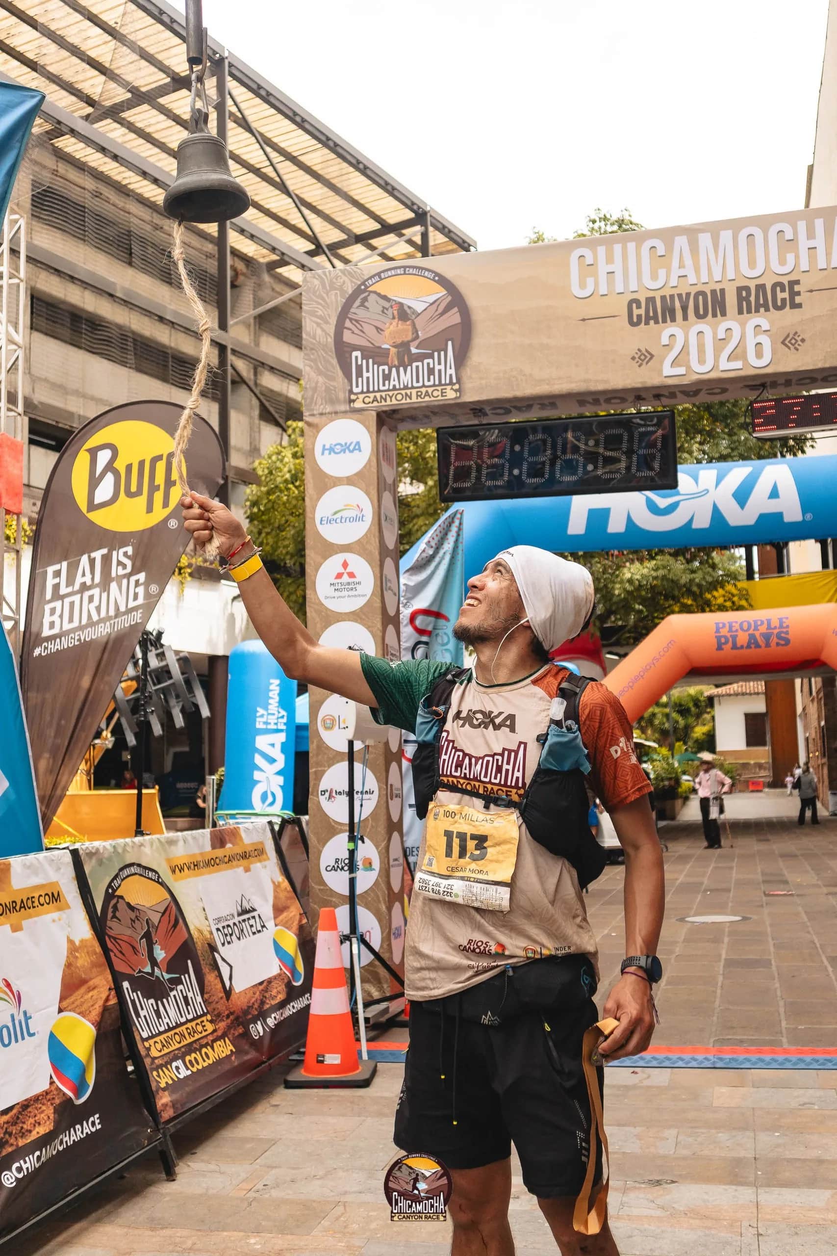 Finisher celebrates with his medal under the 2026 finish gantry