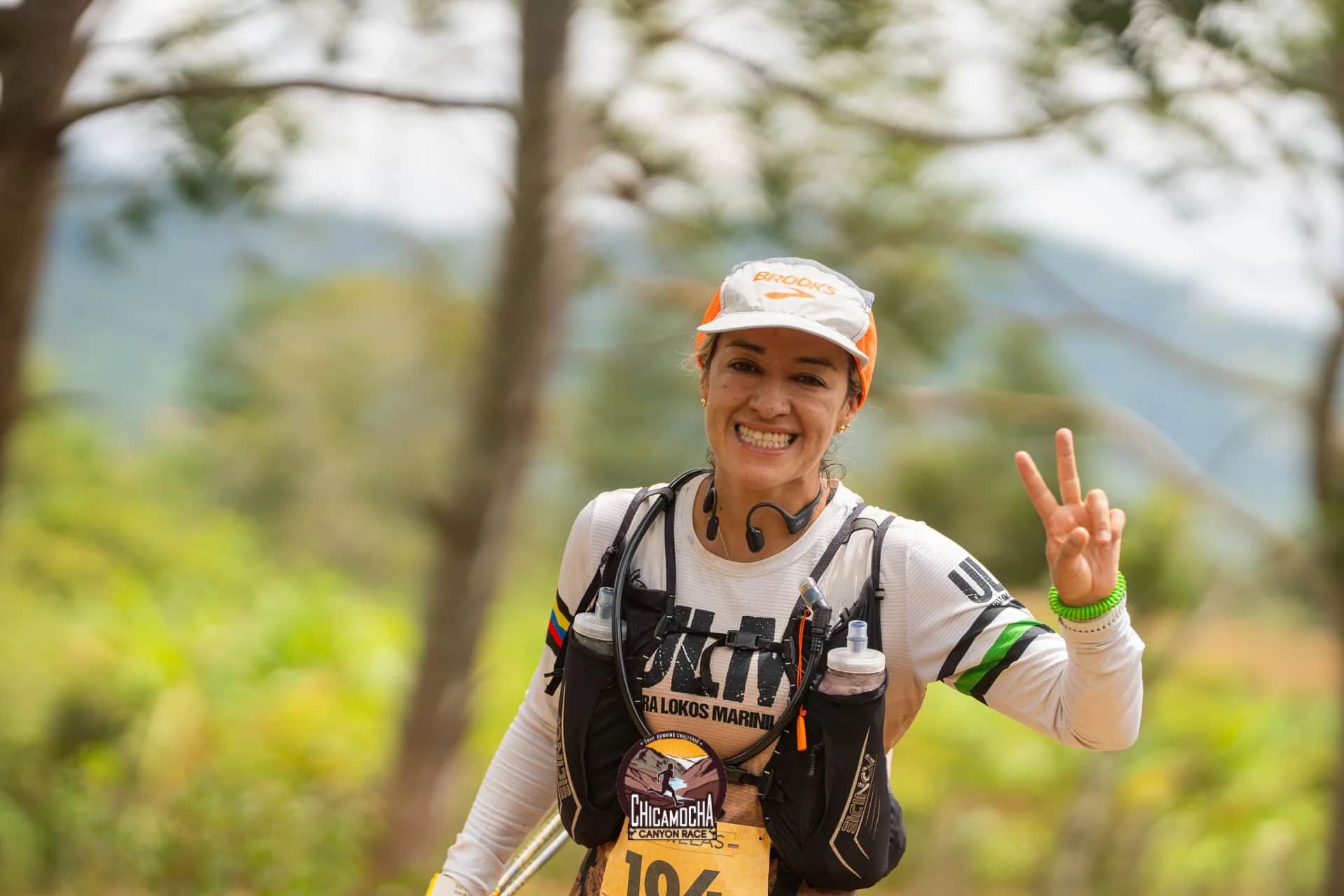Runner smiles and flashes a peace sign on the trail