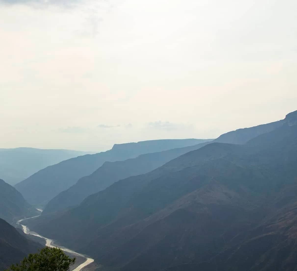 The Chicamocha River winds between the canyon mountains under a hazy sky