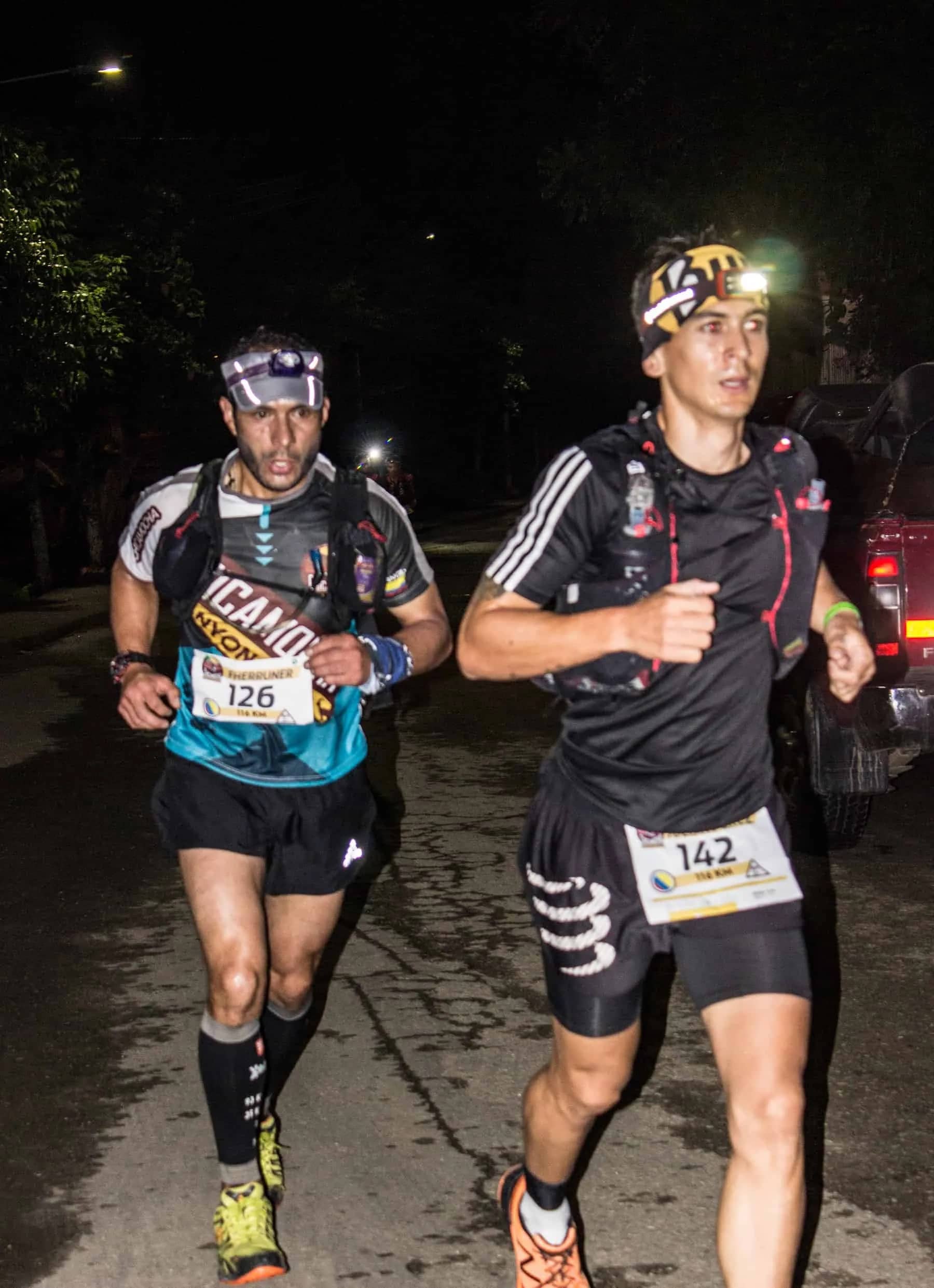 Two runners with headlamps pushing on through the night
