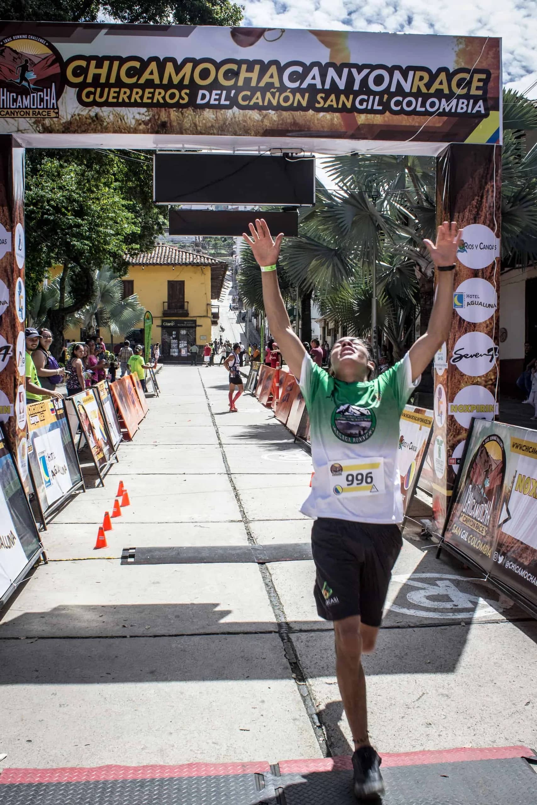 Runner crossing the finish with arms raised under the race arch