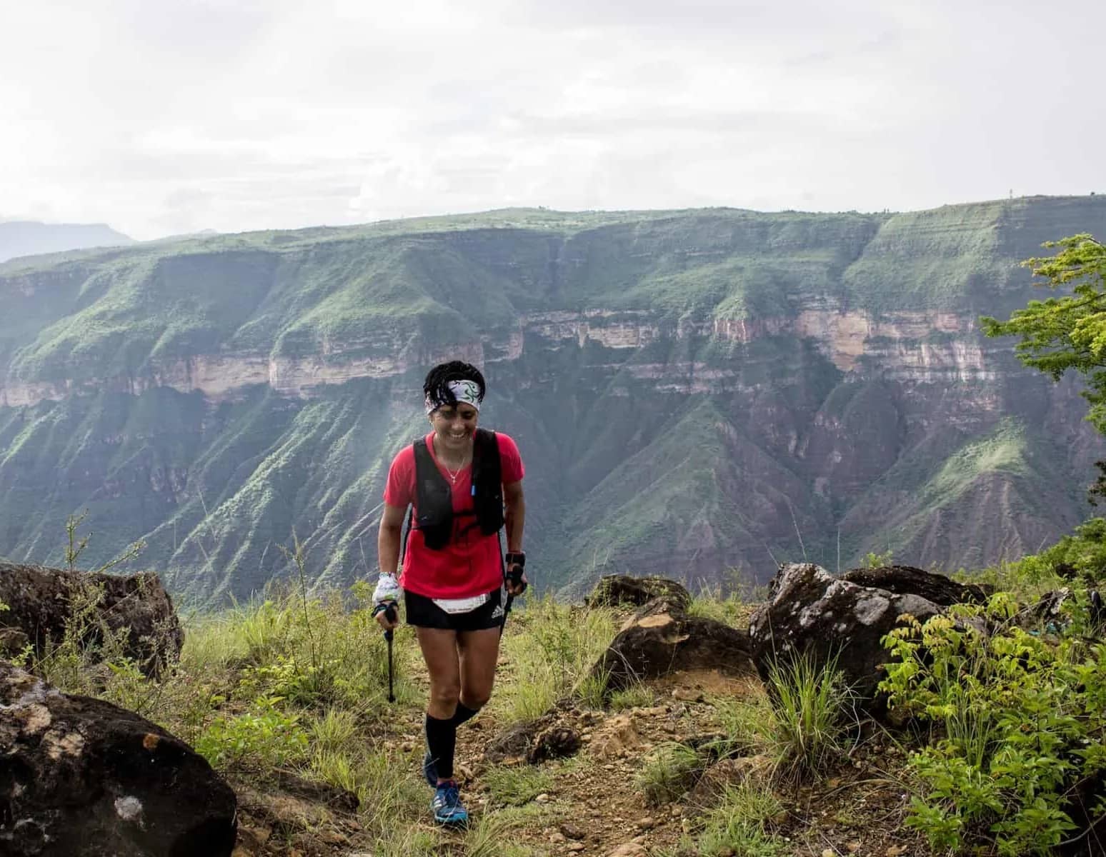 Runner with poles in front of the canyon walls under a cloudy sky
