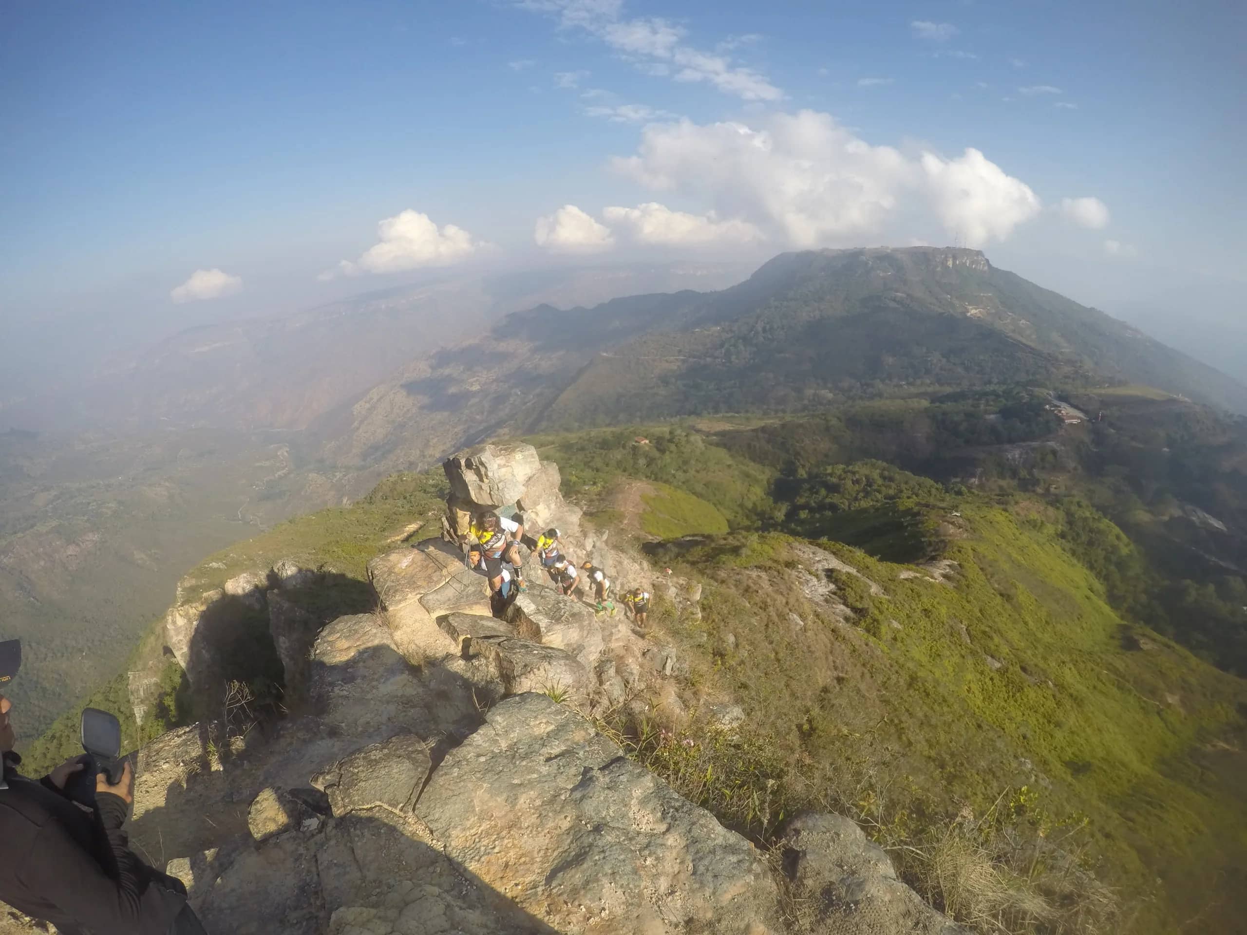 Rocky summit above the canyon with a green valley and mountains beyond