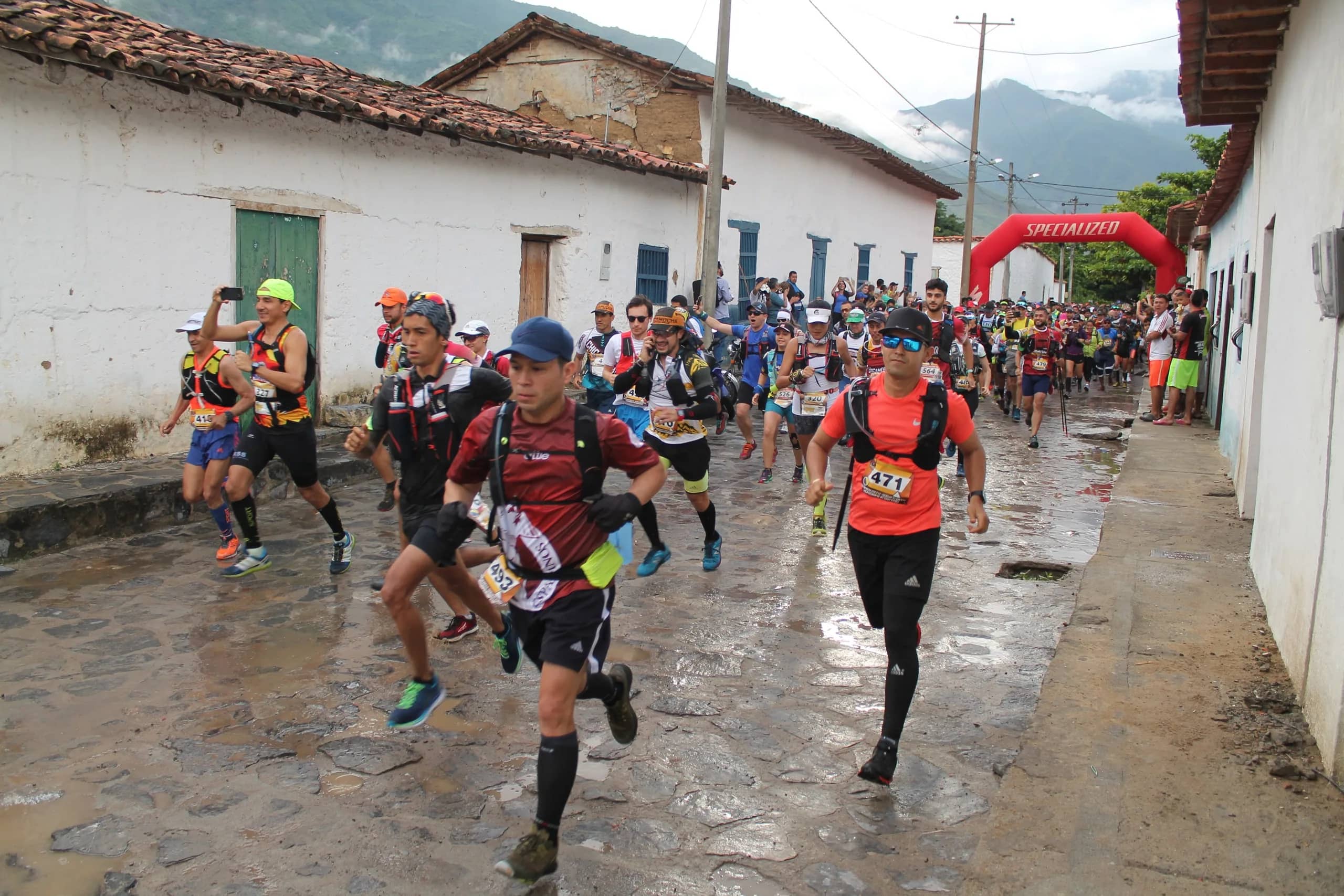Runners set off along a wet village street lined with white houses and tiled roofs