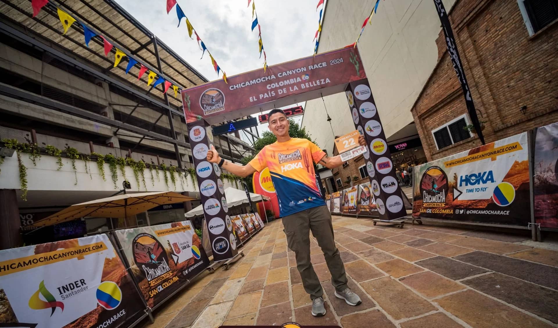 Runner celebrating under the 2024 finish arch bearing the slogan Colombia, the country of beauty