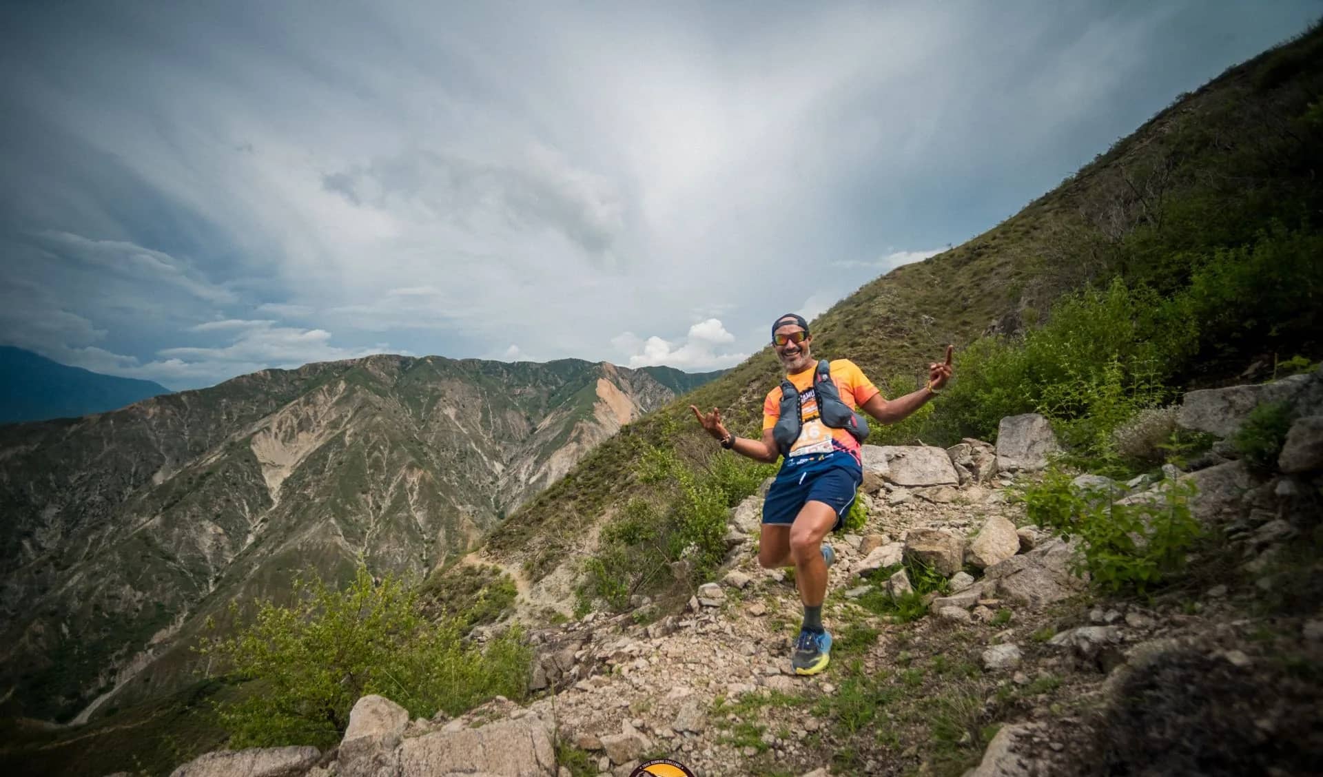Runner on a rocky trail with canyon slopes and storm clouds behind
