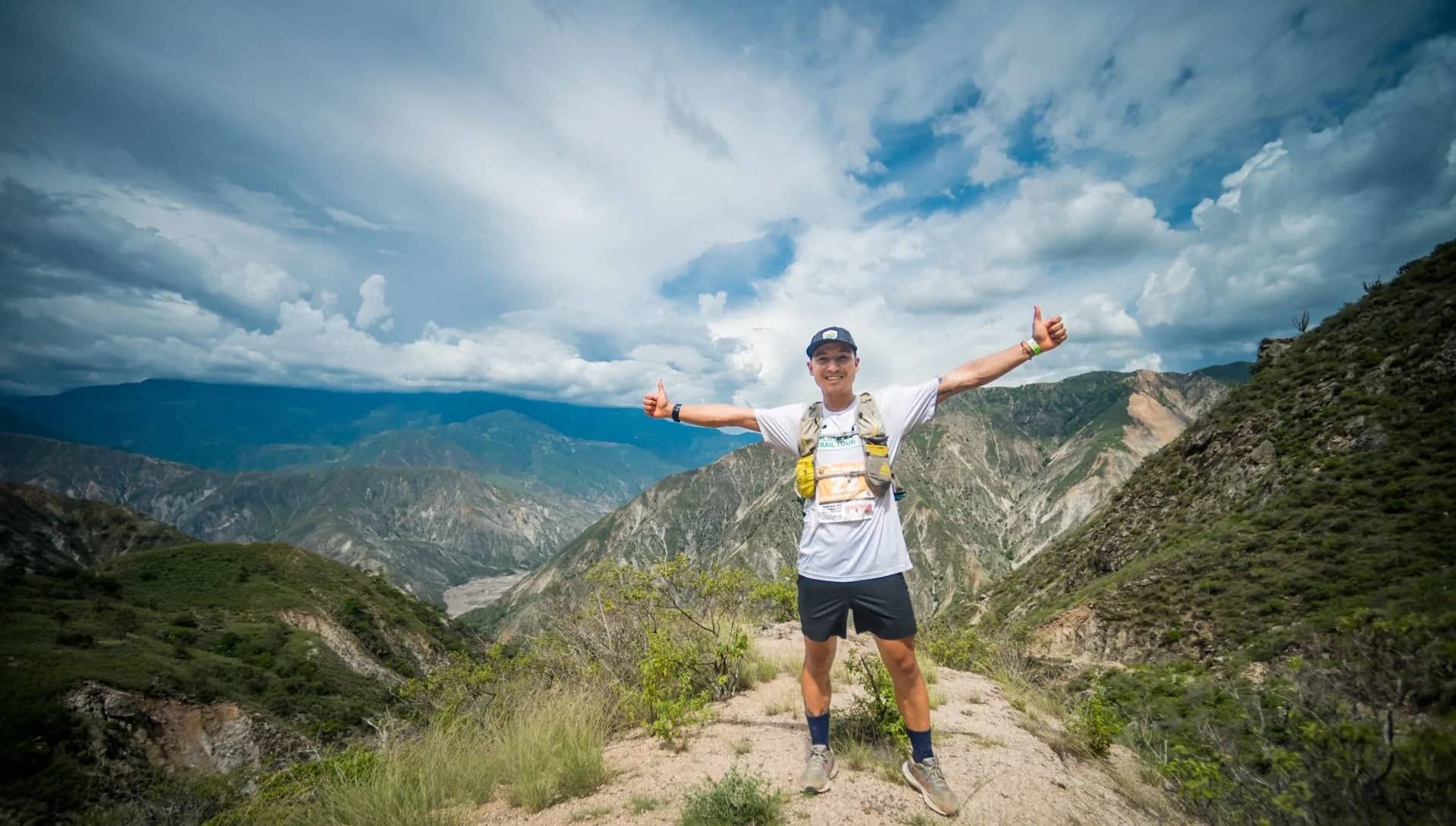 Runner with arms outstretched at the top of a trail above the Chicamocha Canyon