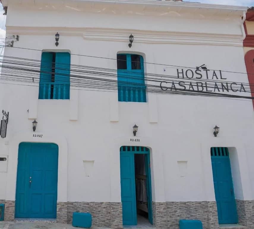 White facade with turquoise doors and windows of Hostal Casa Blanca