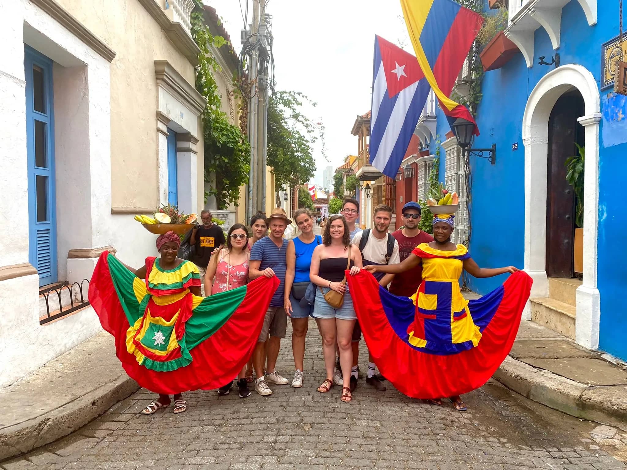 Group of travelers with palenquera women in colorful dresses on a Cartagena street