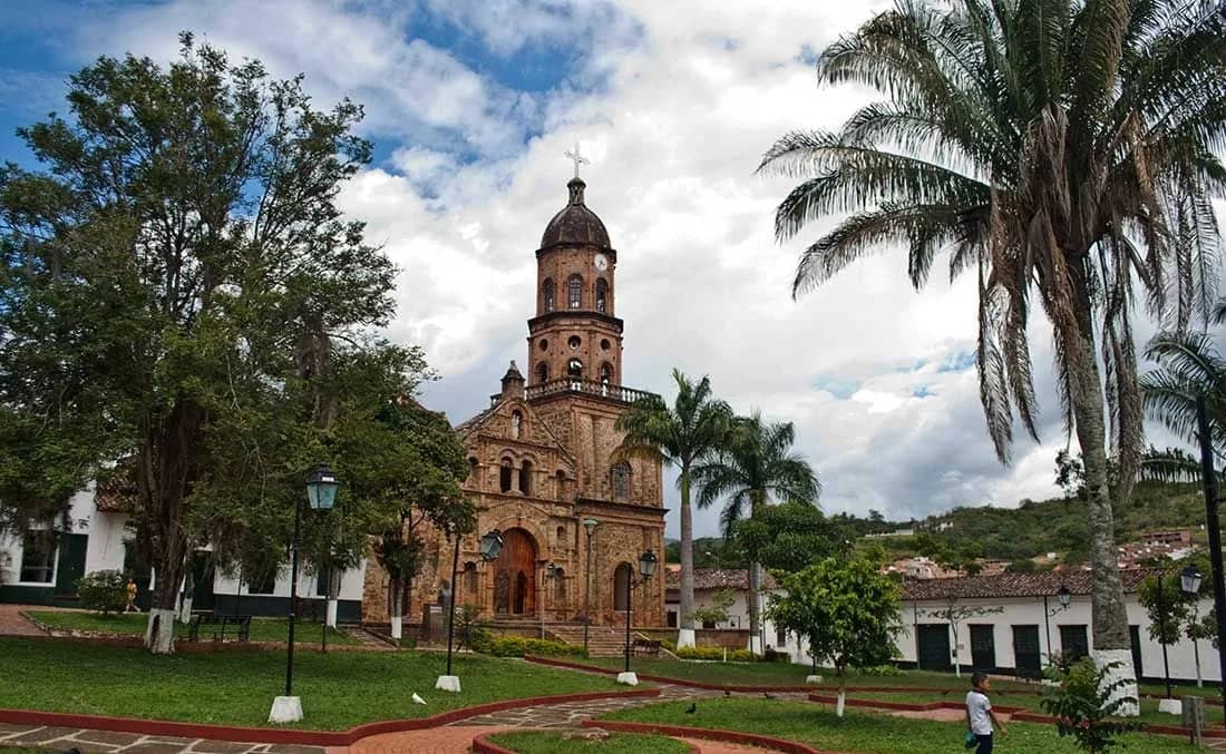 Iglesia colonial de Curití frente a un parque con palmeras