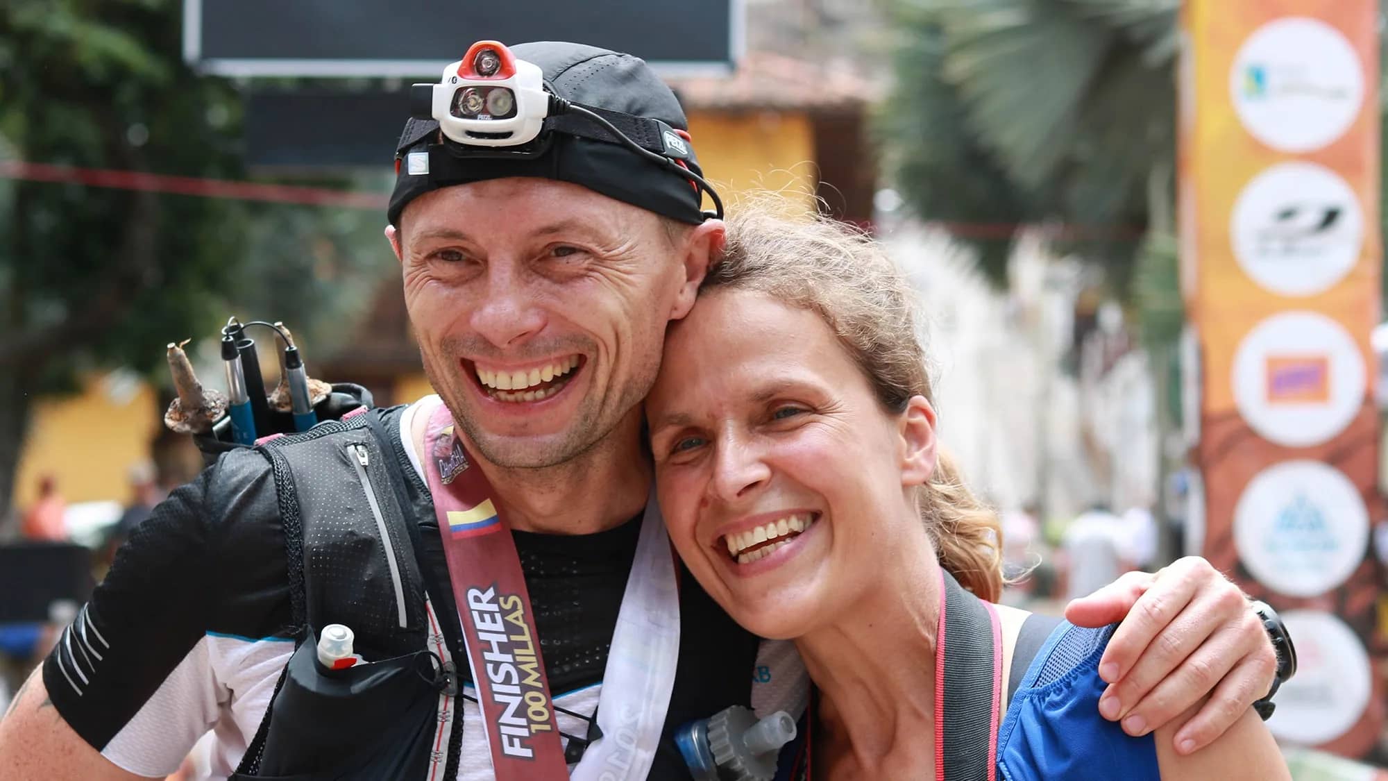 100-mile finisher, medal around his neck, hugs his supporter with a big smile